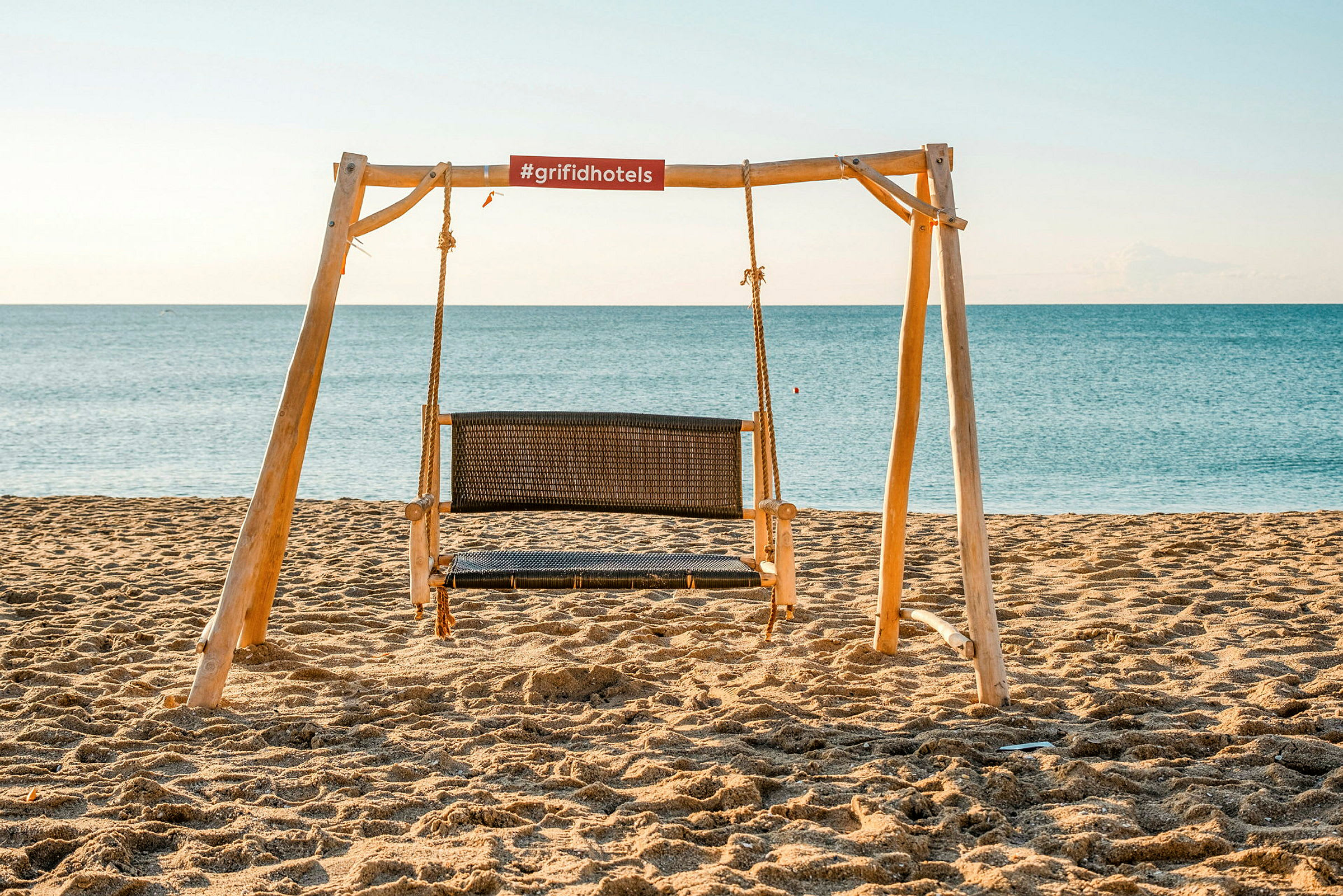 En trehuske med en sittehuske på en sandstrand ved havet. (AI-generert tekst)