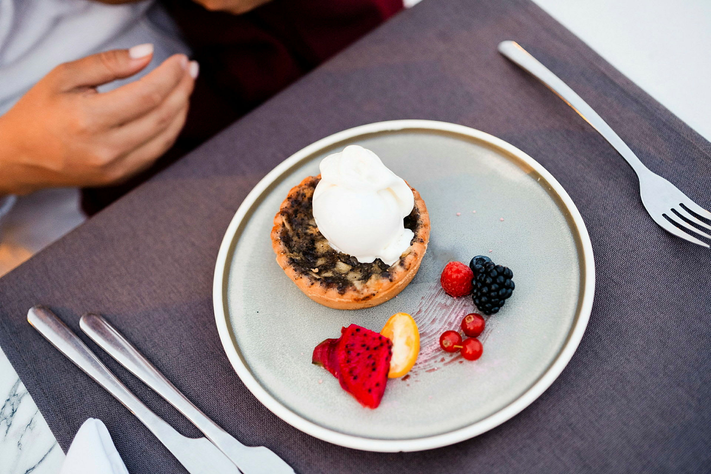 En dessert på en tallerken, inkludert en pai med iskrem og ulike frukter. (AI-generert tekst)