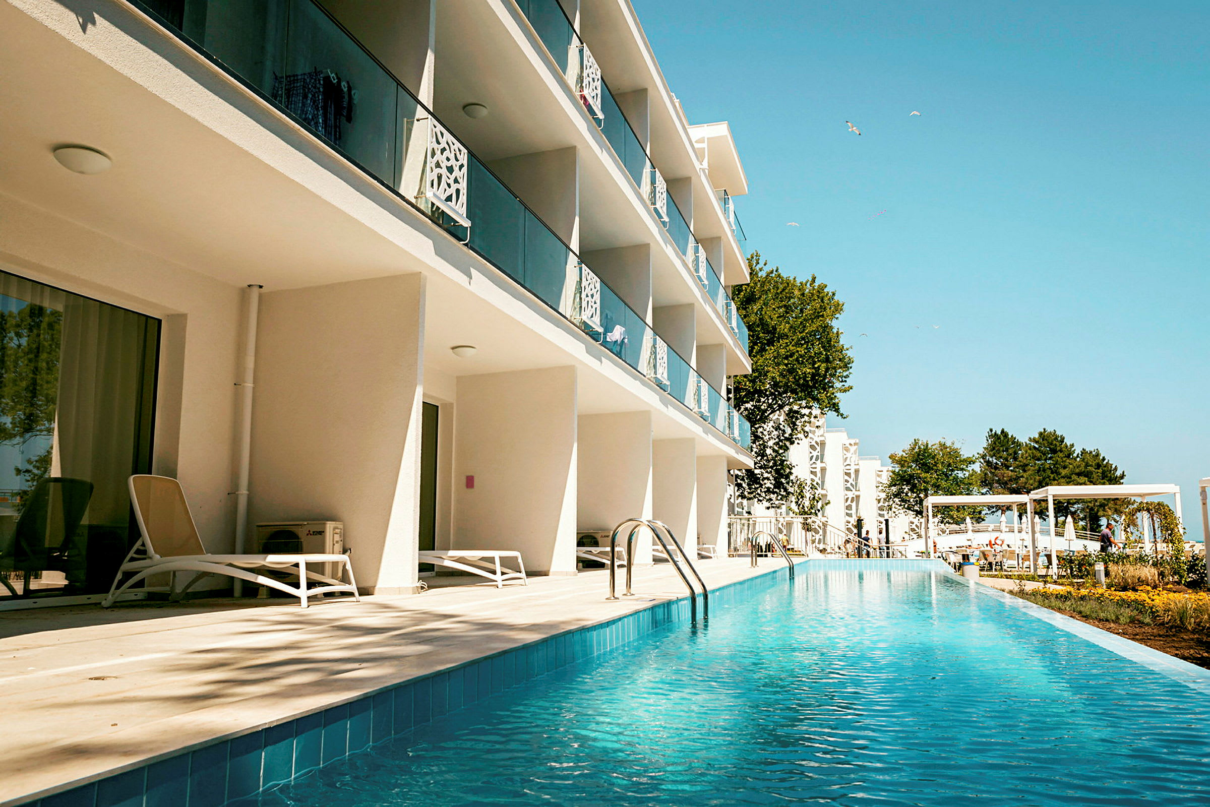Hotellbygning med balkonger og bassengområde. (AI-generert tekst)