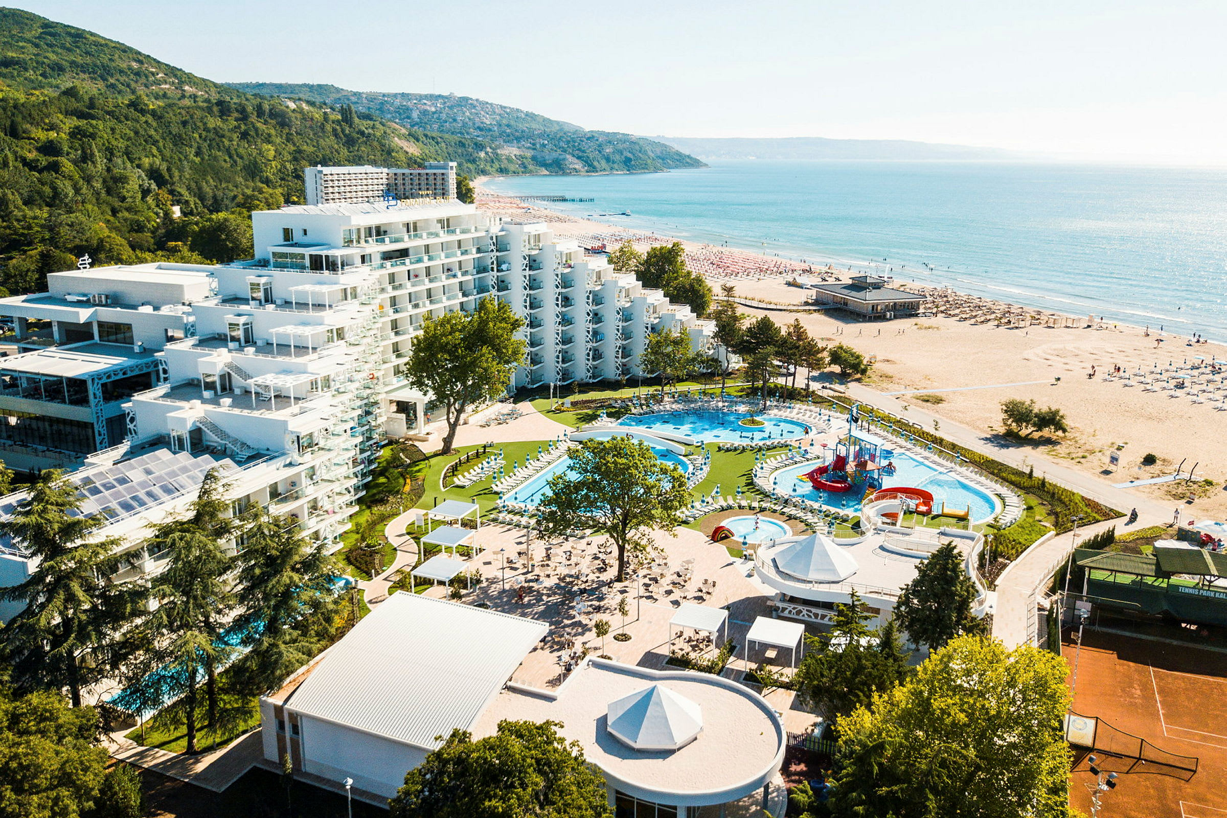 Bilde av et hotellkompleks med bassenger og lekeplass ved stranden. (AI-generert tekst)