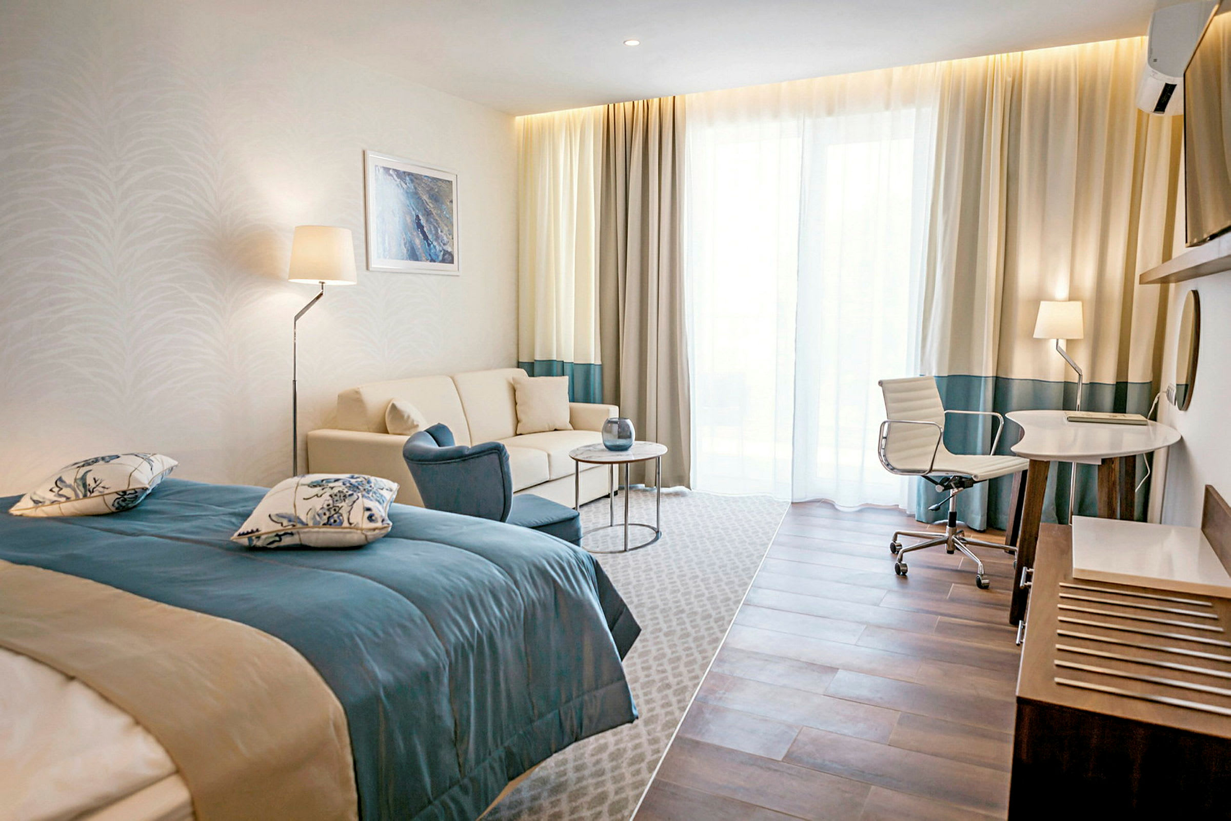 Et hotellrom med en seng, sofa, bord og skrivebord med stol. (AI-generert tekst)