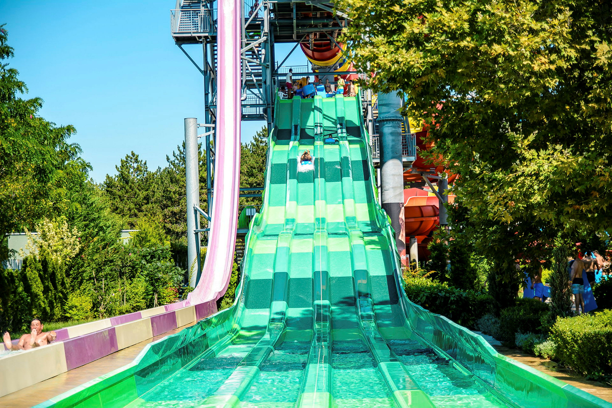 Grønn vannsklie med flere spor i en vannpark. (AI-generert tekst)