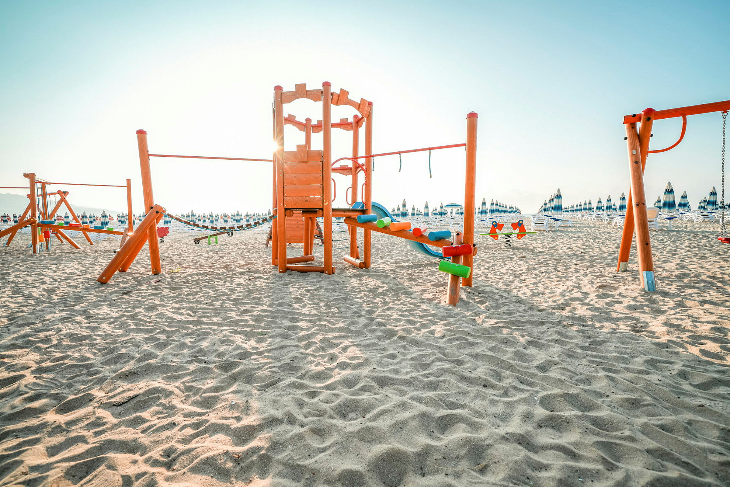 Lekeplass med sand og solsenger i bakgrunnen. (AI-generert tekst)