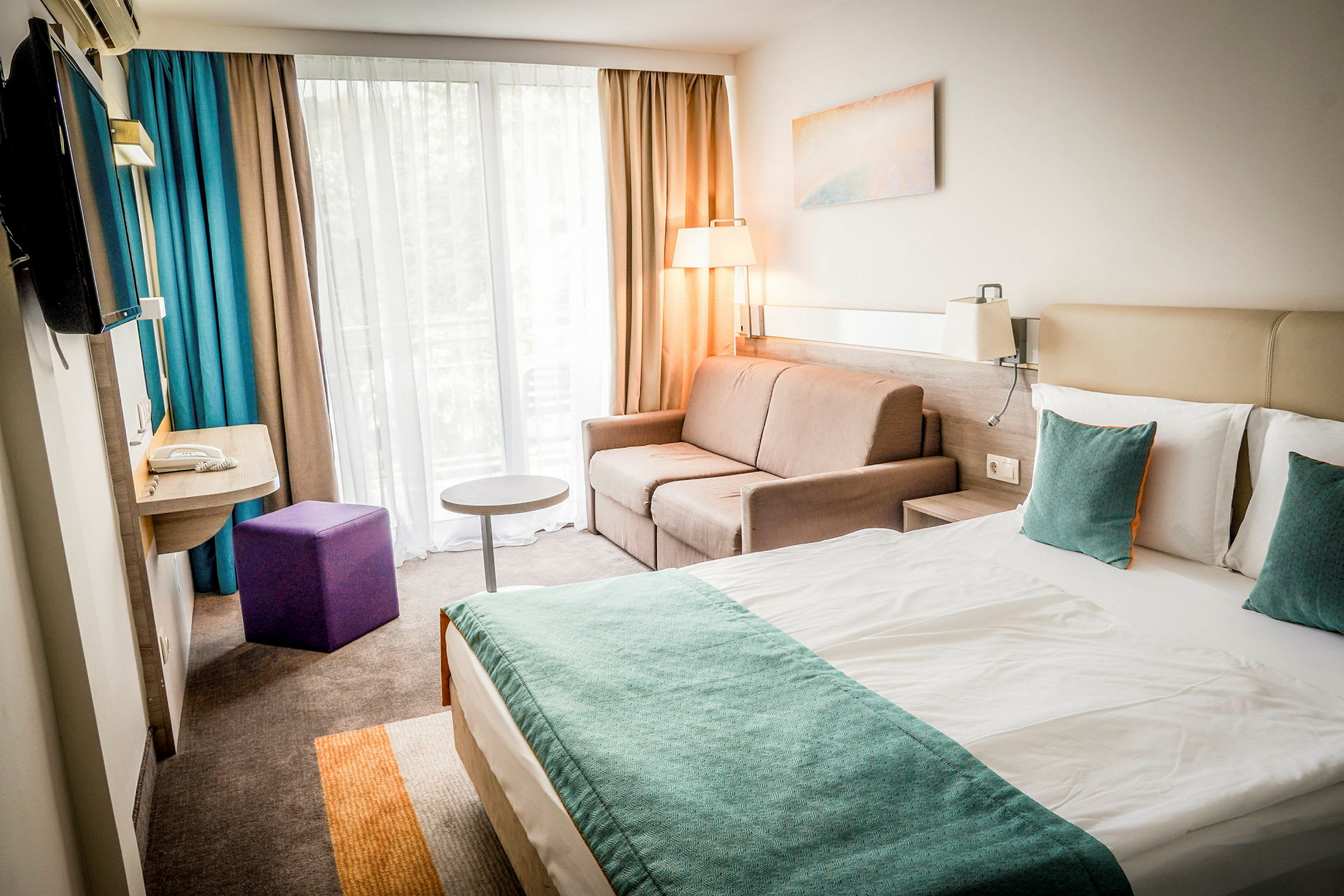 Et moderne hotellrom med en dobbeltseng, sofa og vindu med gardiner. (AI-generert tekst)