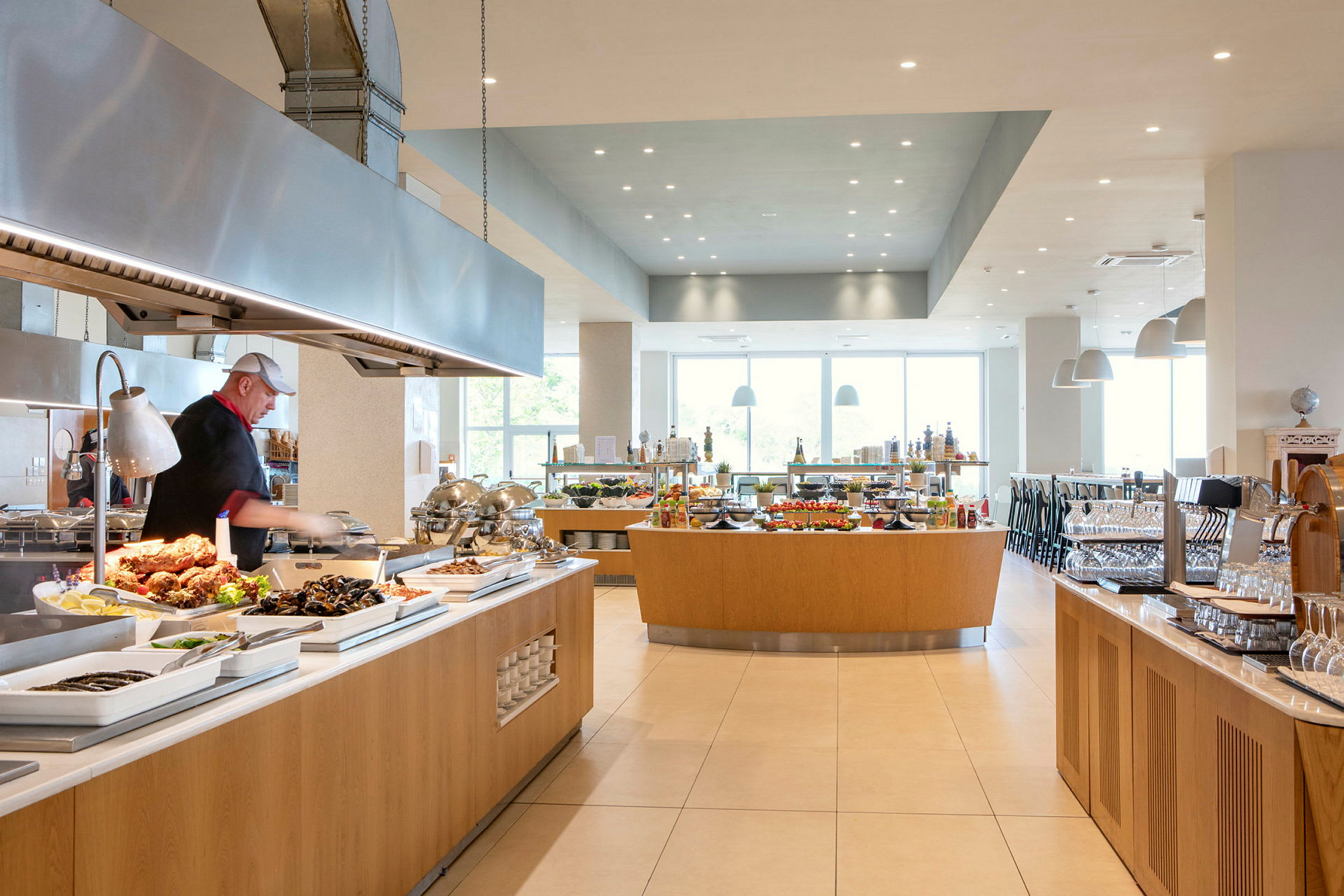 En servering med buffet med forskjellige retter og en kokk som jobber. (AI-generert tekst)