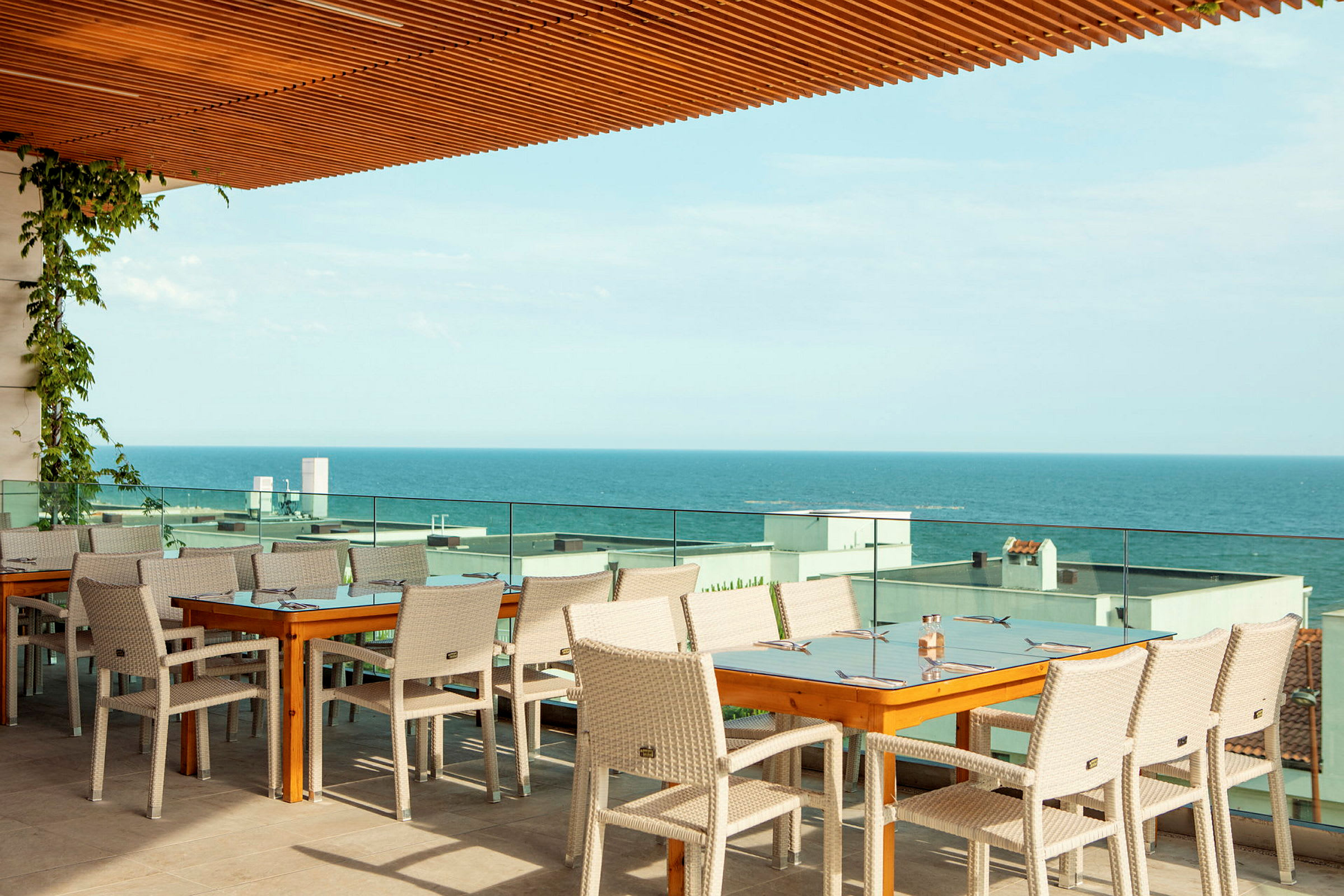Restaurantbord og stoler på en terrasse med utsikt over havet. (AI-generert tekst)