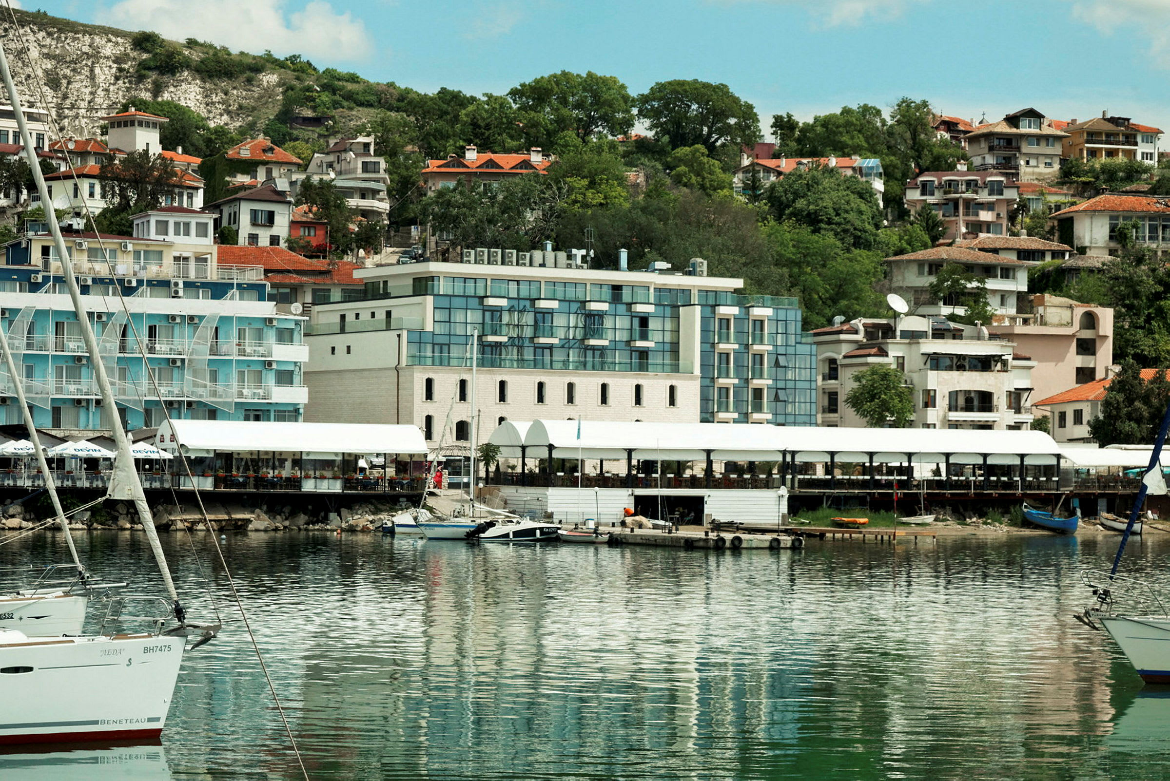 Bilde av en havn med båter og bygninger i bakgrunnen. (AI-generert tekst)