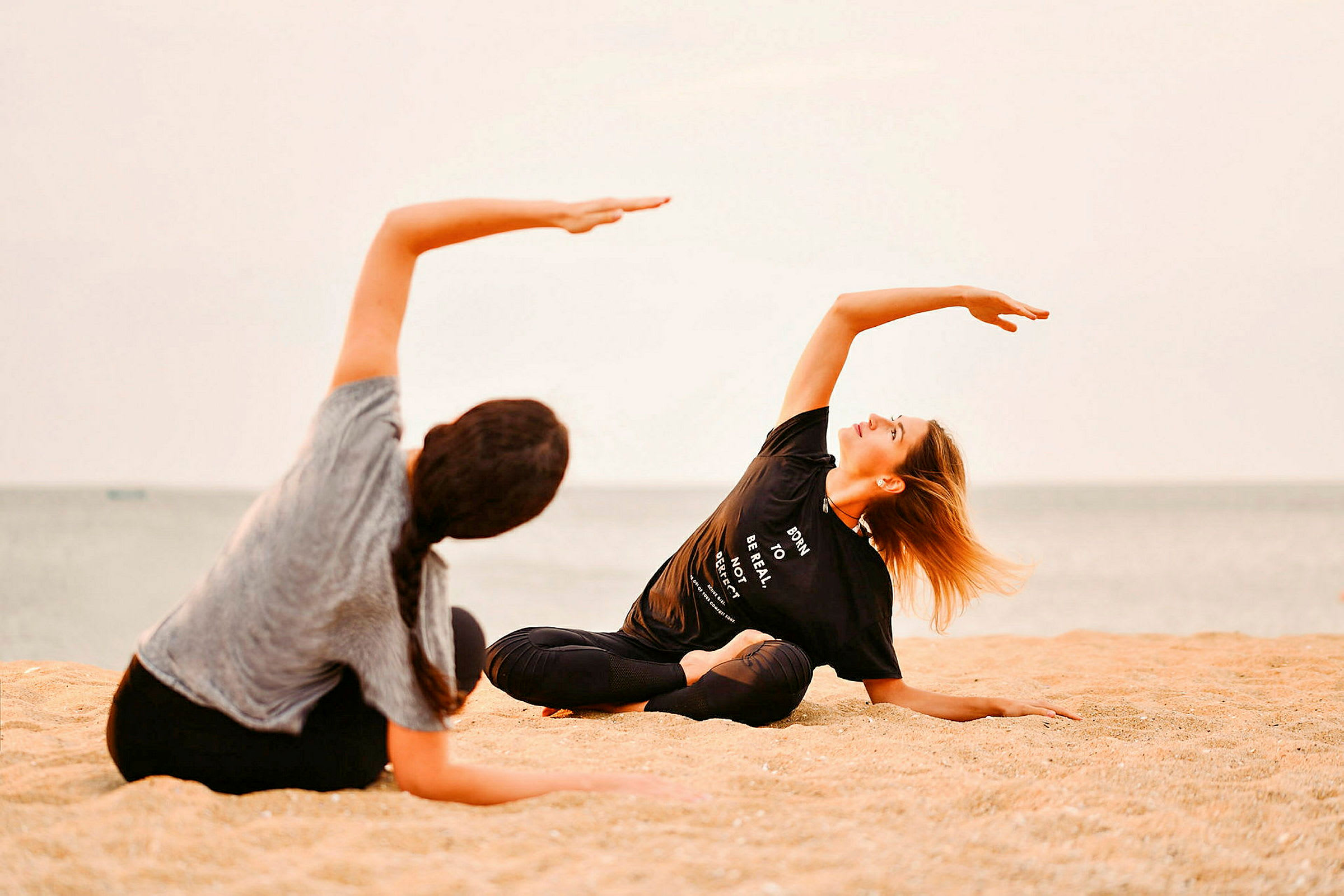 To personer utøver yoga på en strand. (AI-generert tekst)