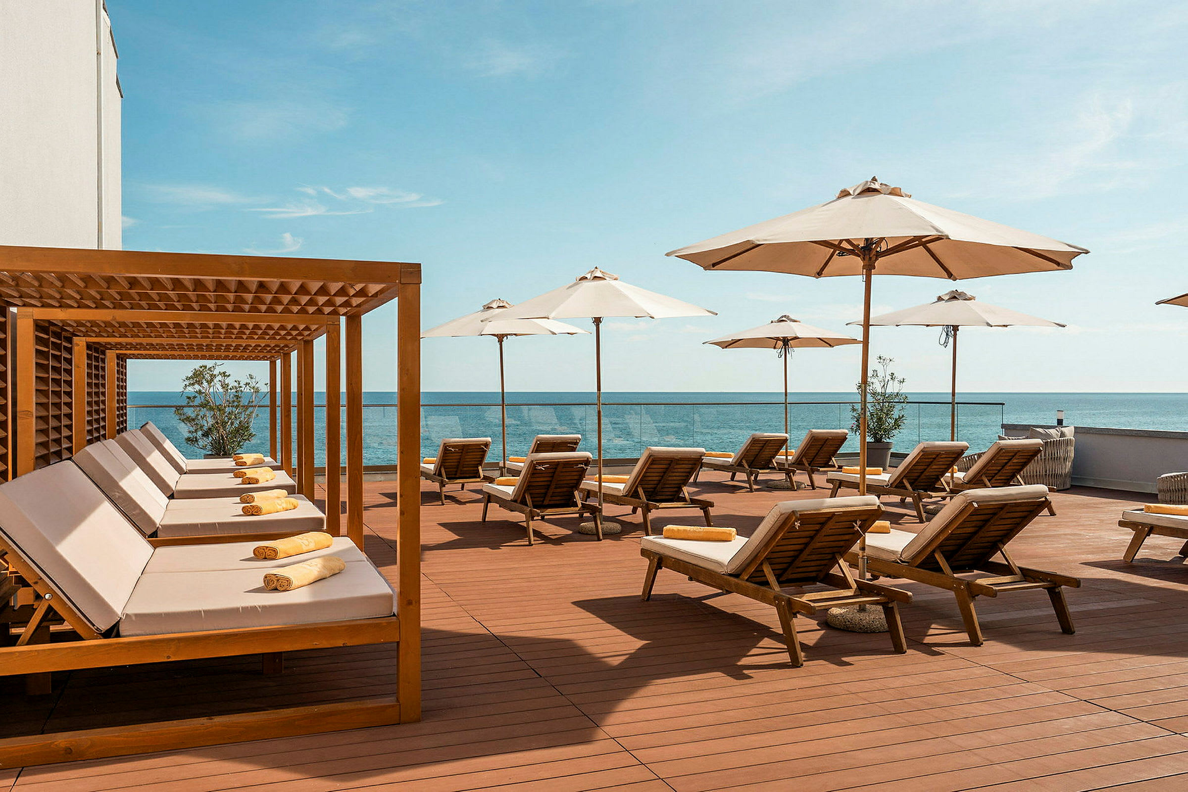 Solsenger under hvite parasoller på en terrasse med utsikt over havet. (AI-generert tekst)