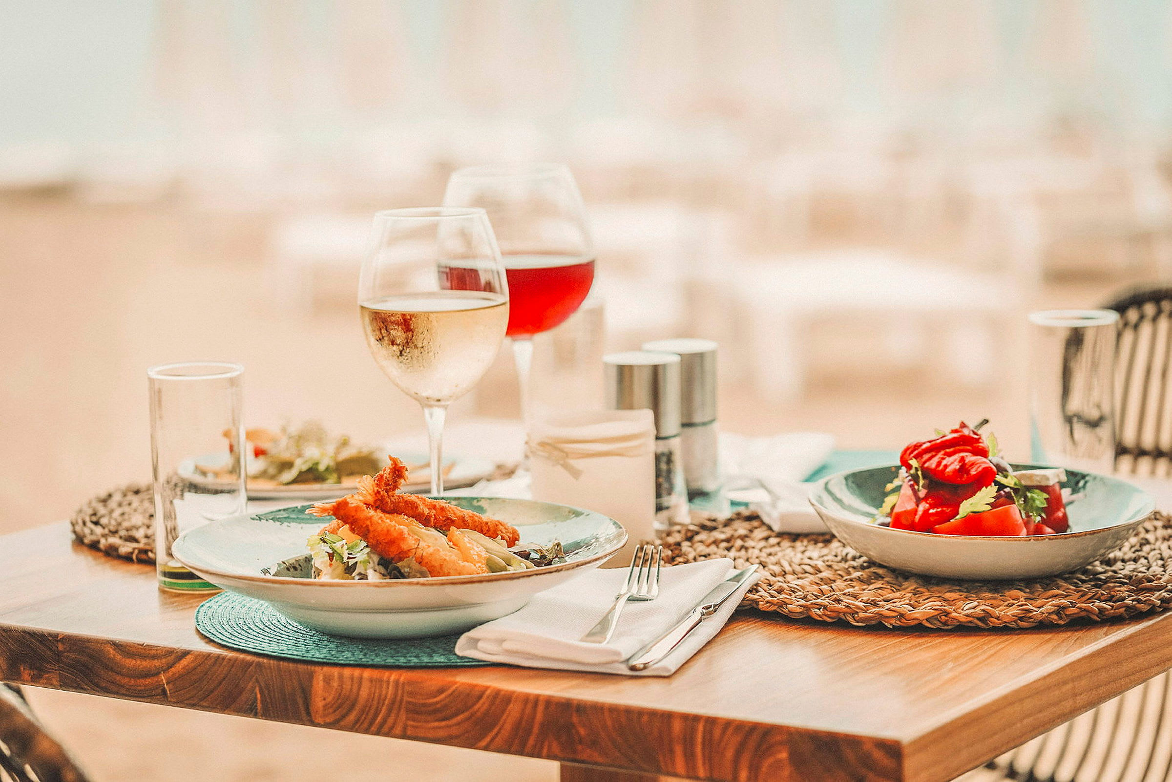 Spisebord med tallerkener som inneholder salat og fritert mat, sammen med vinglass. (AI-generert tekst)
