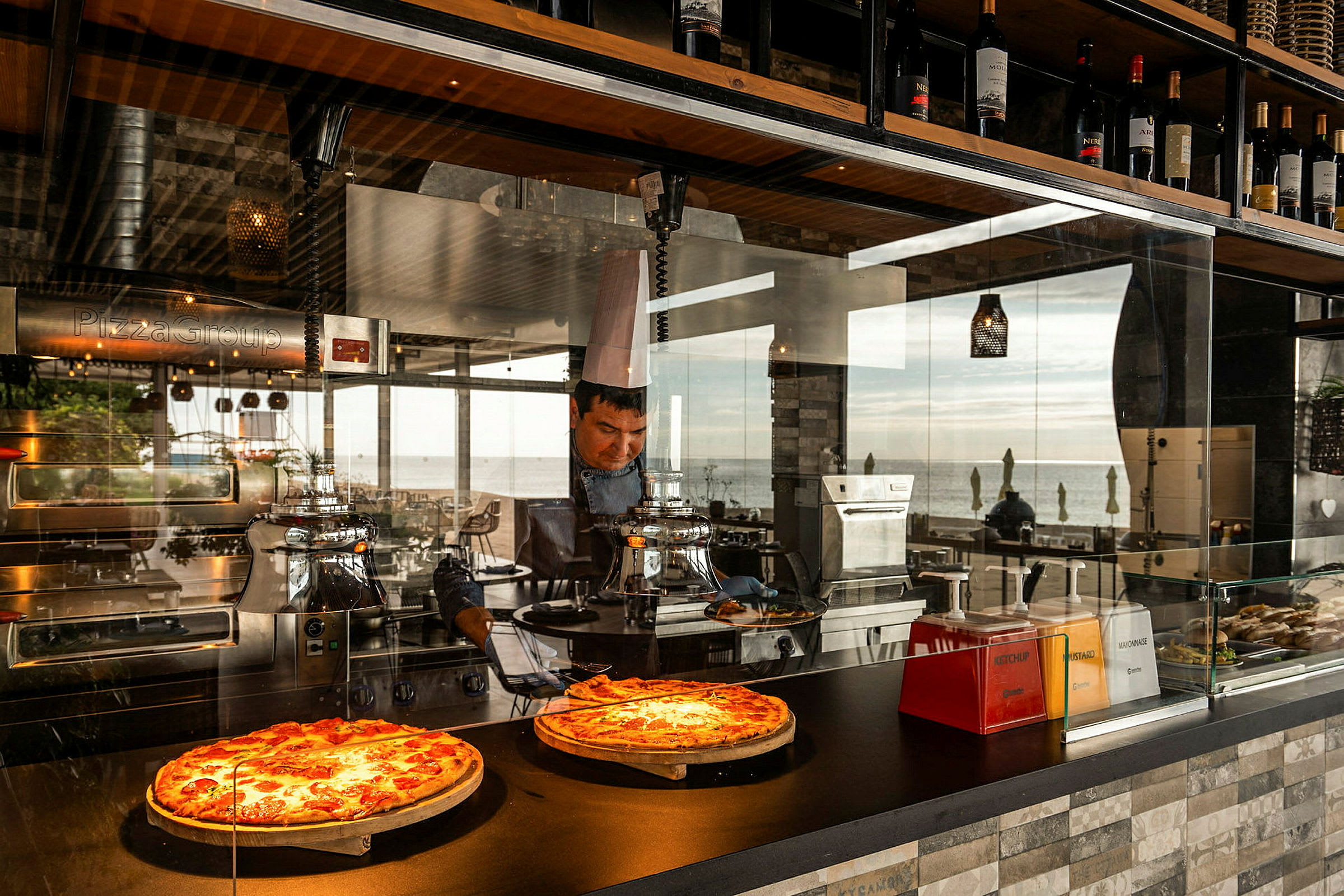 To pizzaer på utstilling i en restaurant med utsikt mot havet. (AI-generert tekst)
