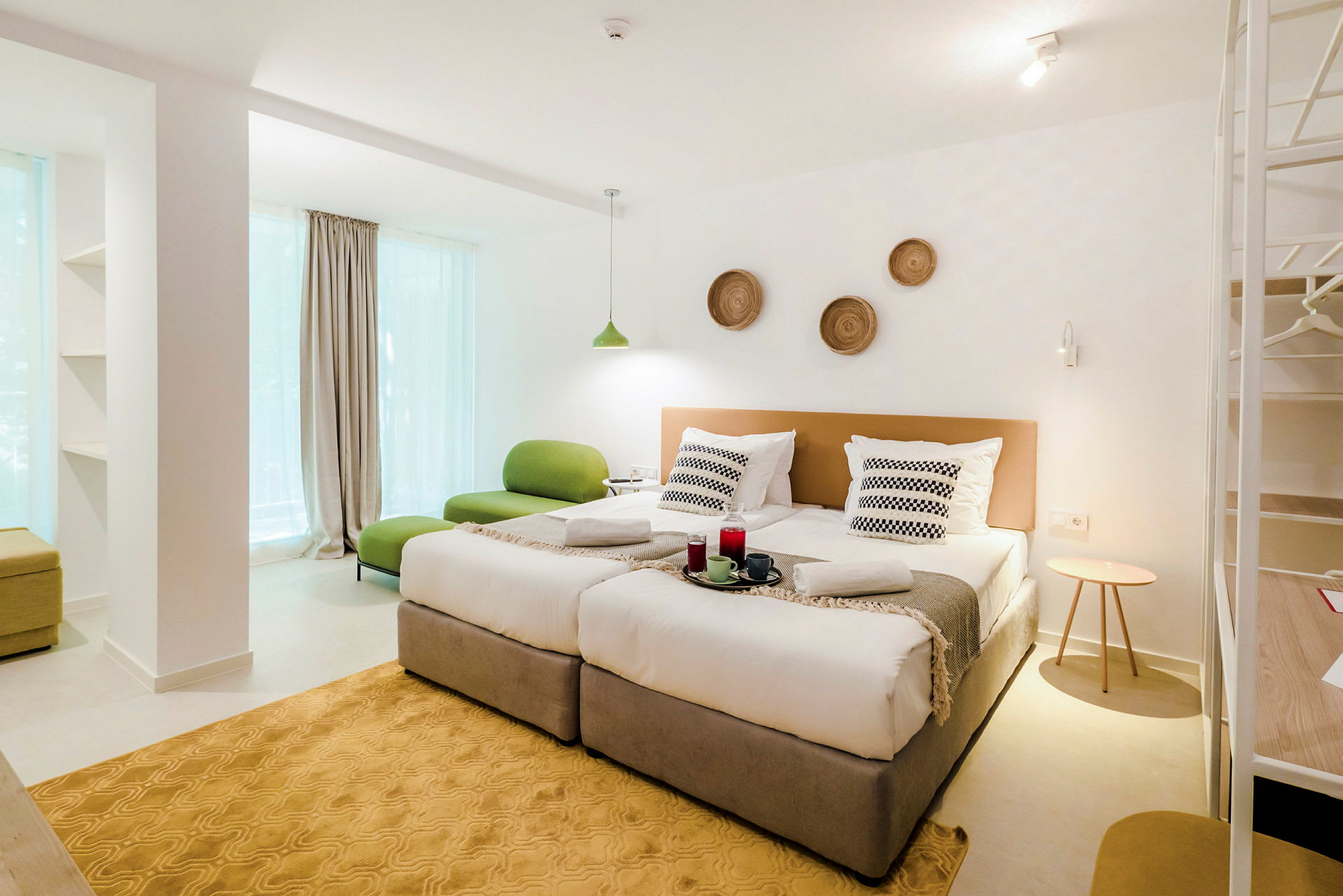 Et moderne hotellrom med to enkeltsenger, grønn sittemøbel og dekorasjoner på veggen. (AI-generert tekst)