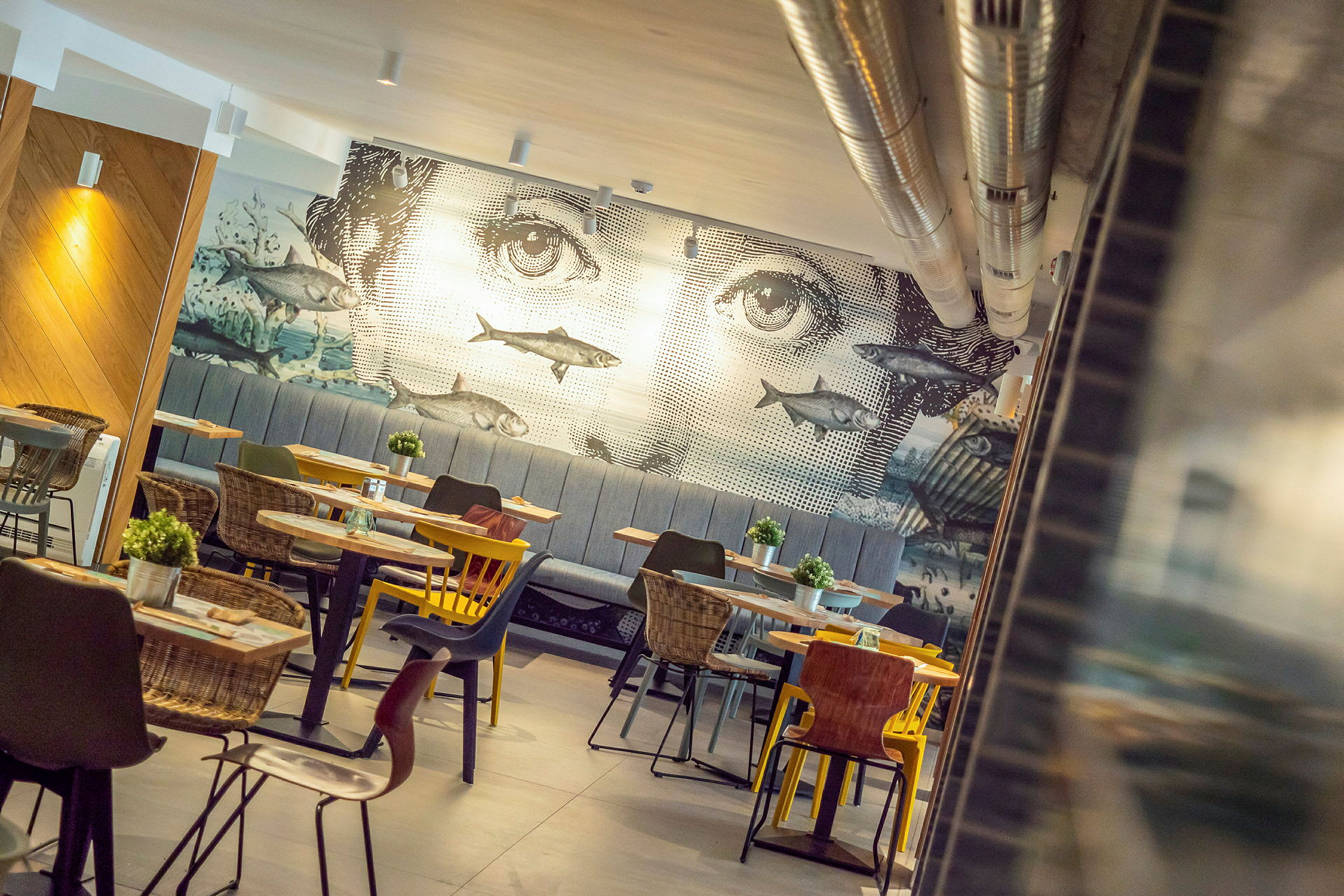 En restaurant med en veggdekor som viser et ansikt og fisker. (AI-generert tekst)