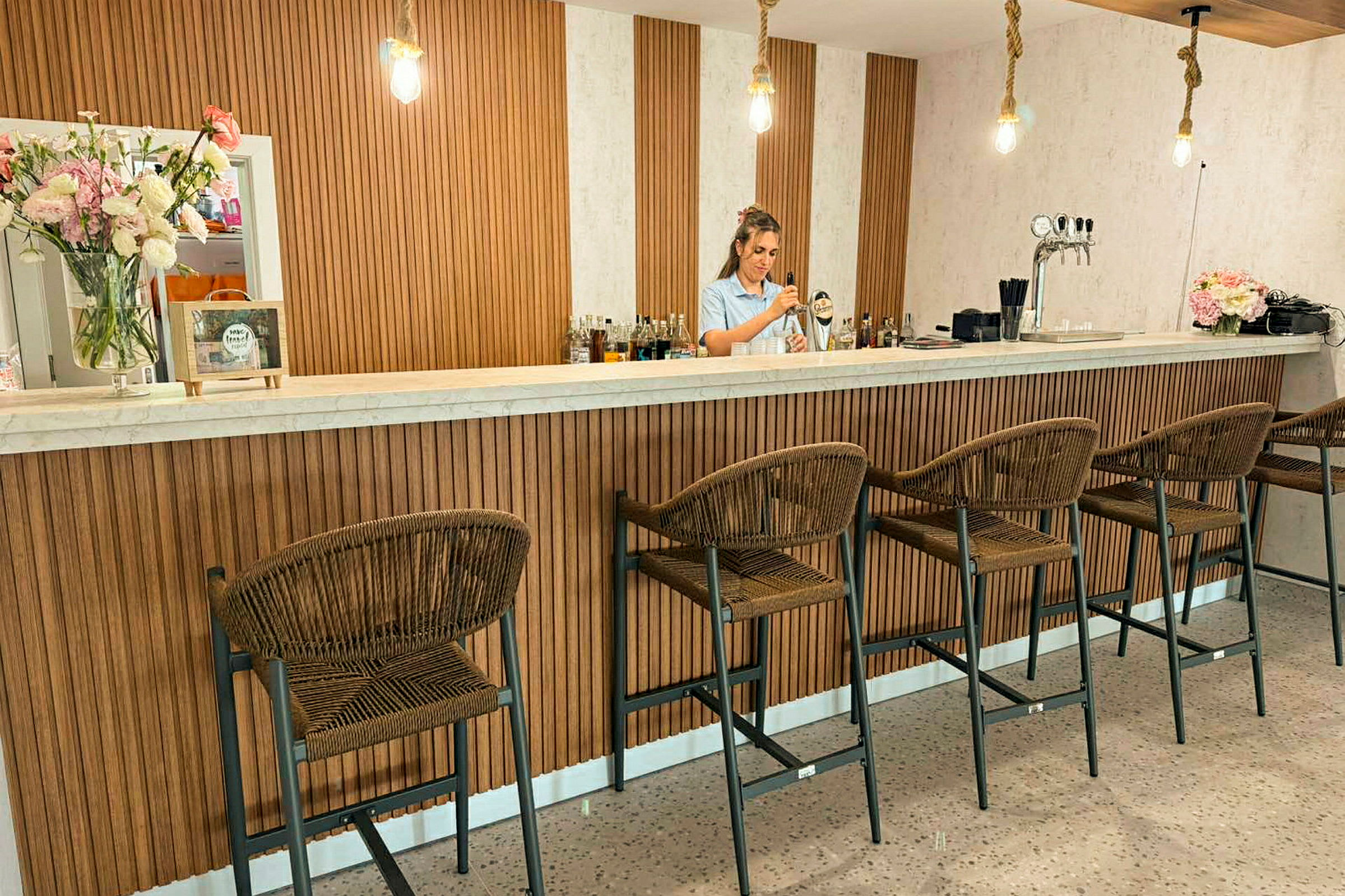 En bar med høye stoler og trematerialer i innredningen. (AI-generert tekst)