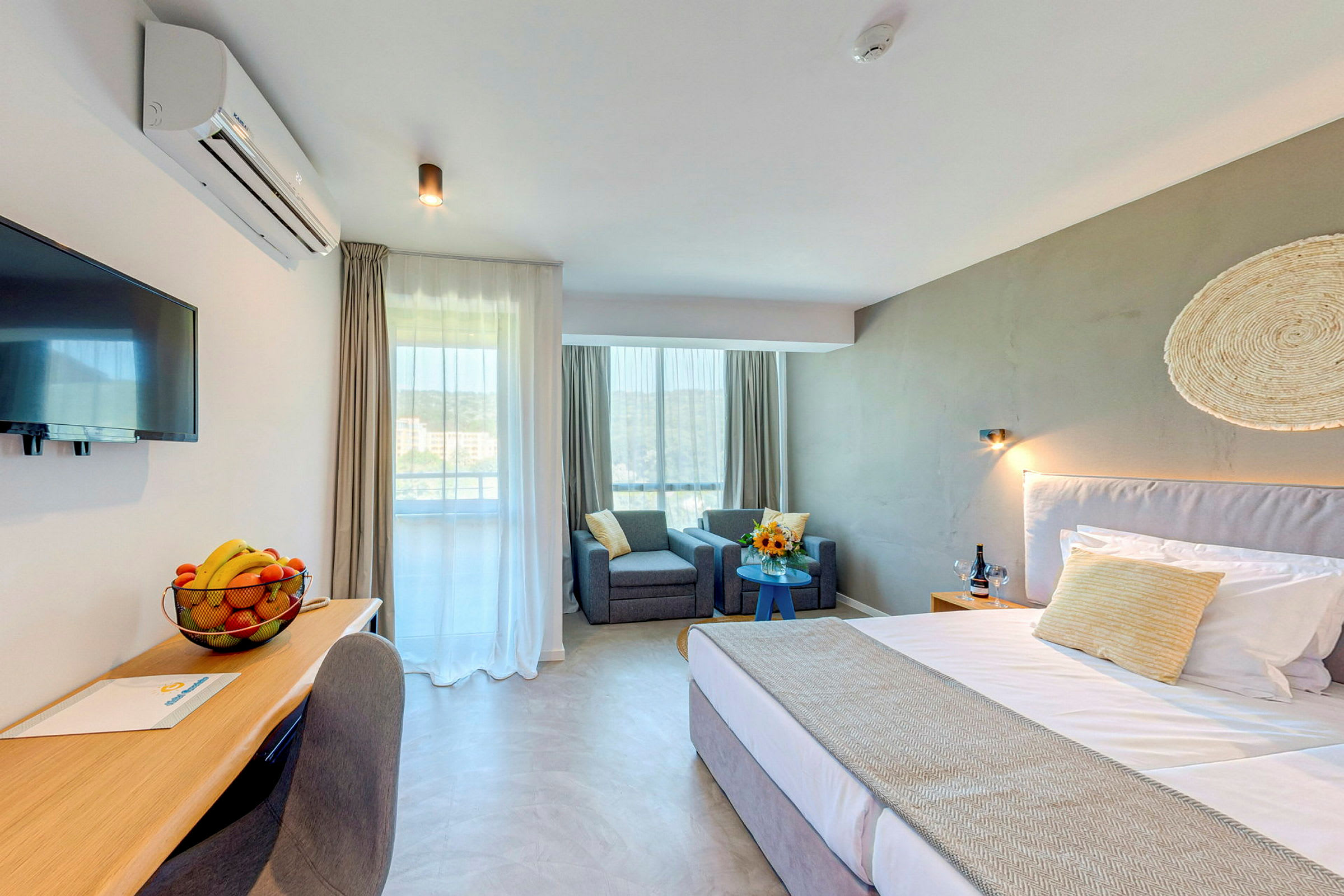 Moderne hotellrom med seng, skrivebord, to lenestoler og vindu. (AI-generert tekst)