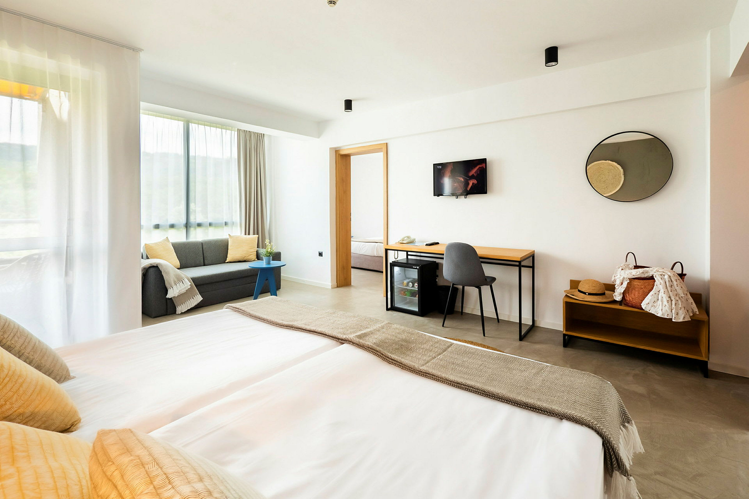 Moderne hotellrom med dobbeltseng, sofa og skrivebord. (AI-generert tekst)