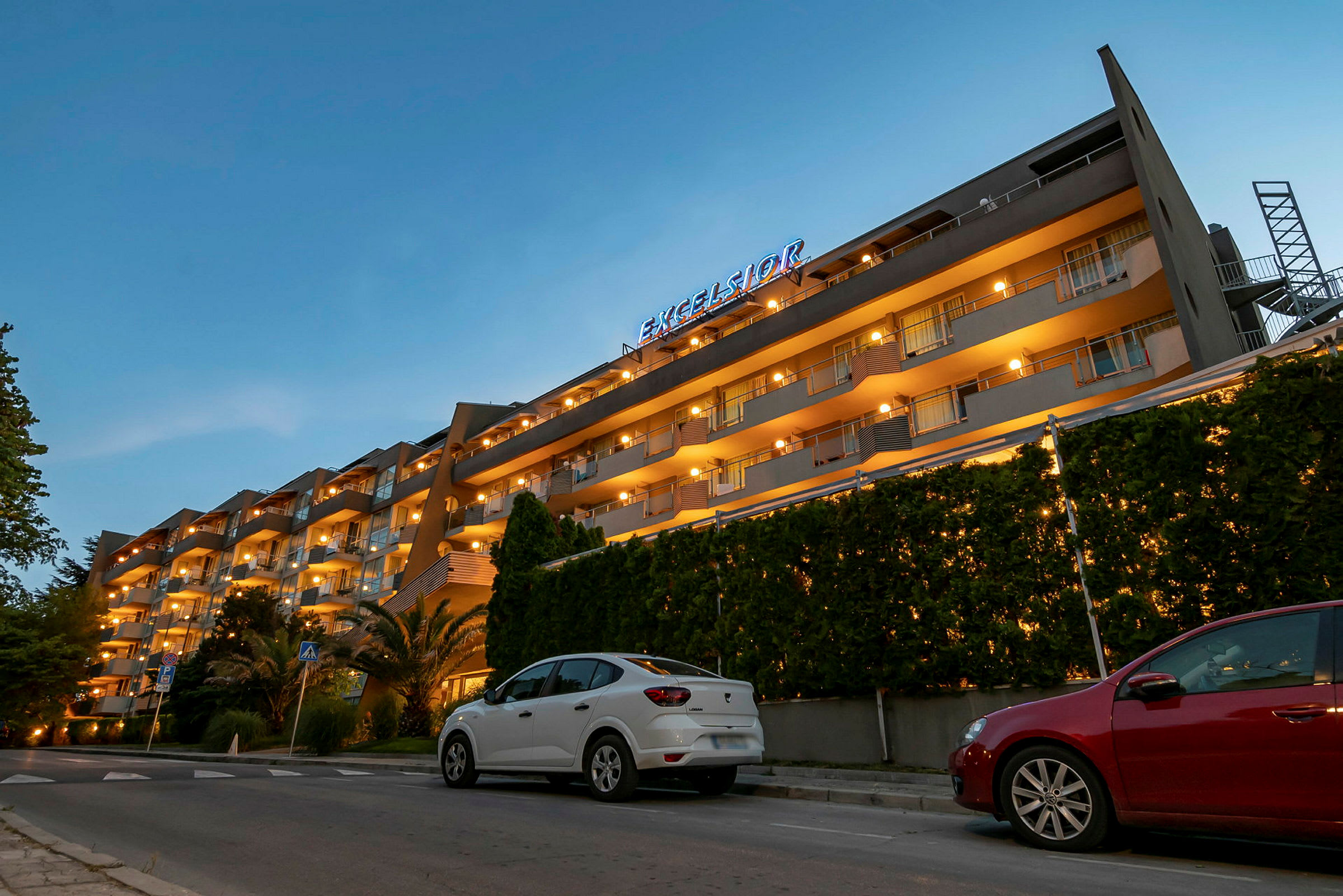 Et hotell med flere etasjer og opplyste balkonger om kvelden. (AI-generert tekst)