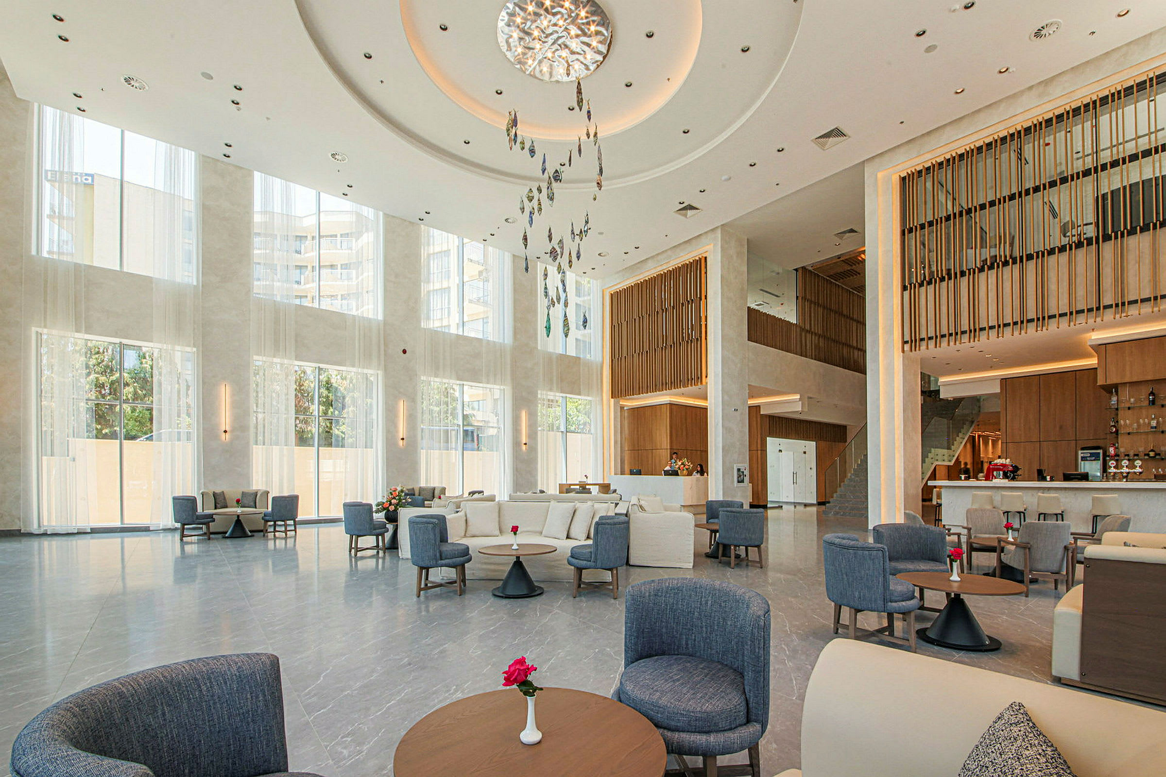 Bilde av en lys hotellobby med store vinduer, moderne interiør og sittegrupper. (AI-generert tekst)
