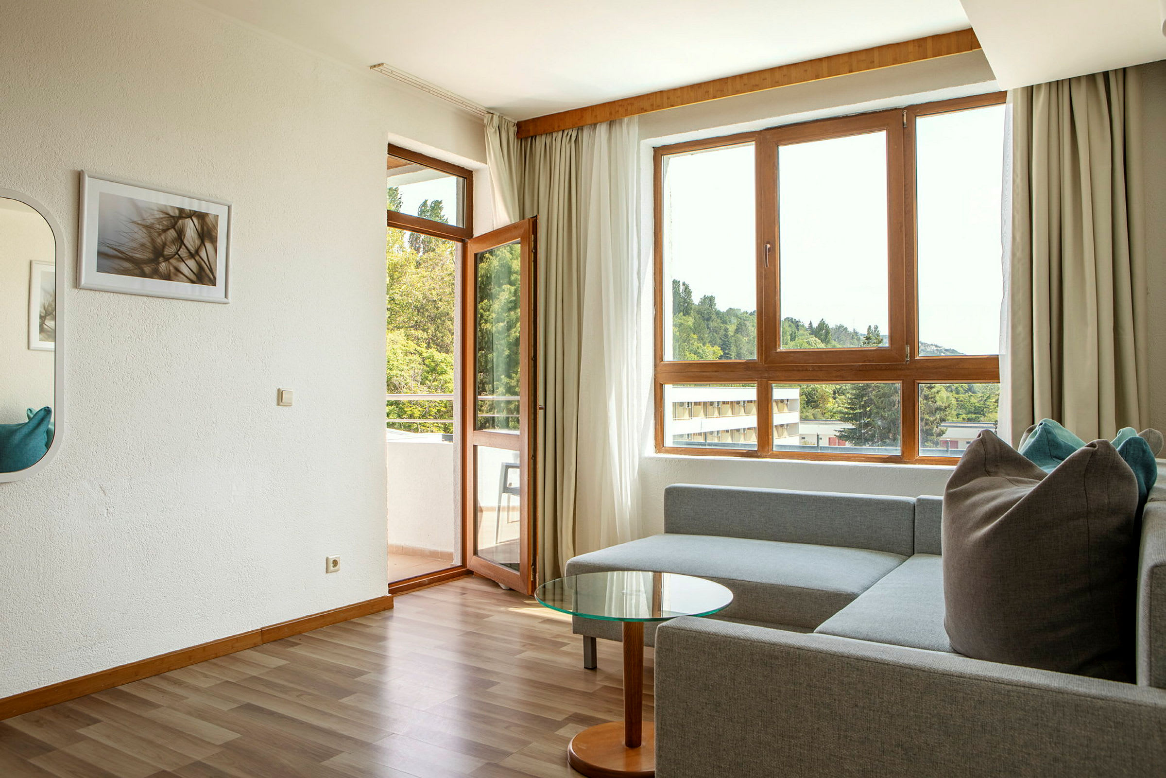 Moderne stue med sofa, glasbord og store vinduer med utsikt. (AI-generert tekst)