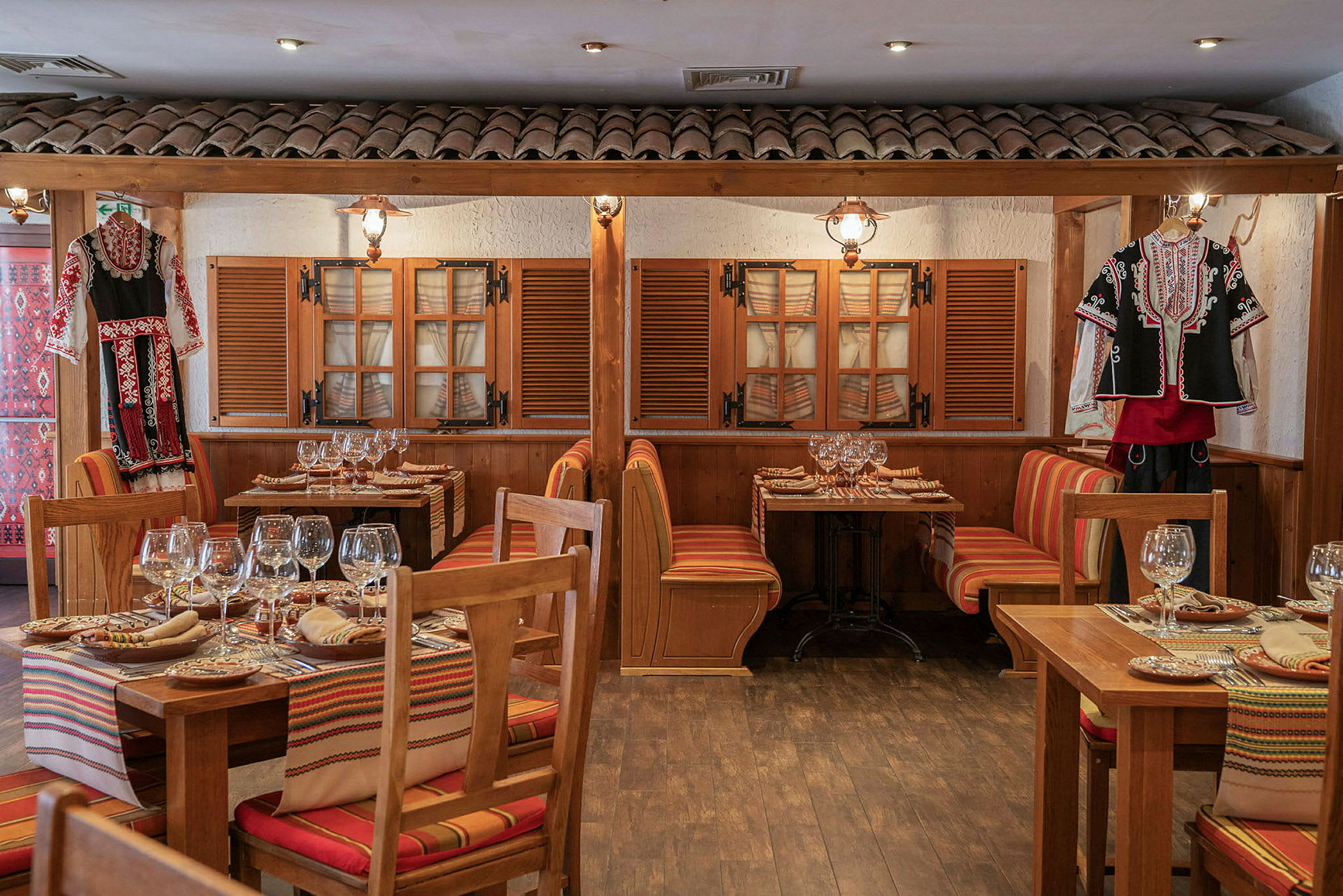 Bilde av en restaurant med tradisjonelle trebord, fargerike sitteputer og folkedrakt som dekorasjon. (AI-generert tekst)
