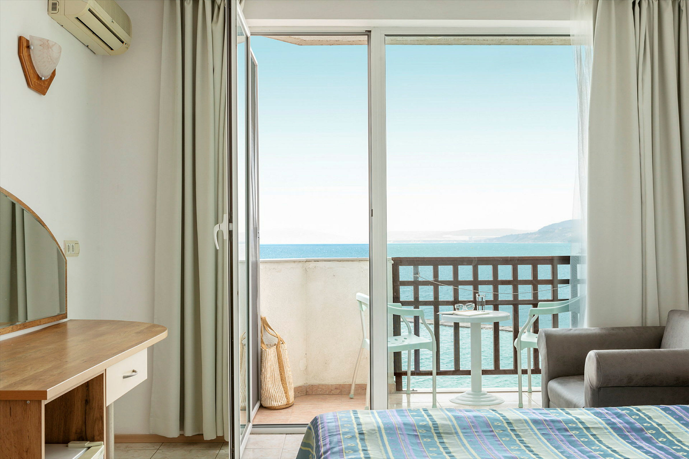 Hotellrom med åpen balkongdør og havutsikt. (AI-generert tekst)