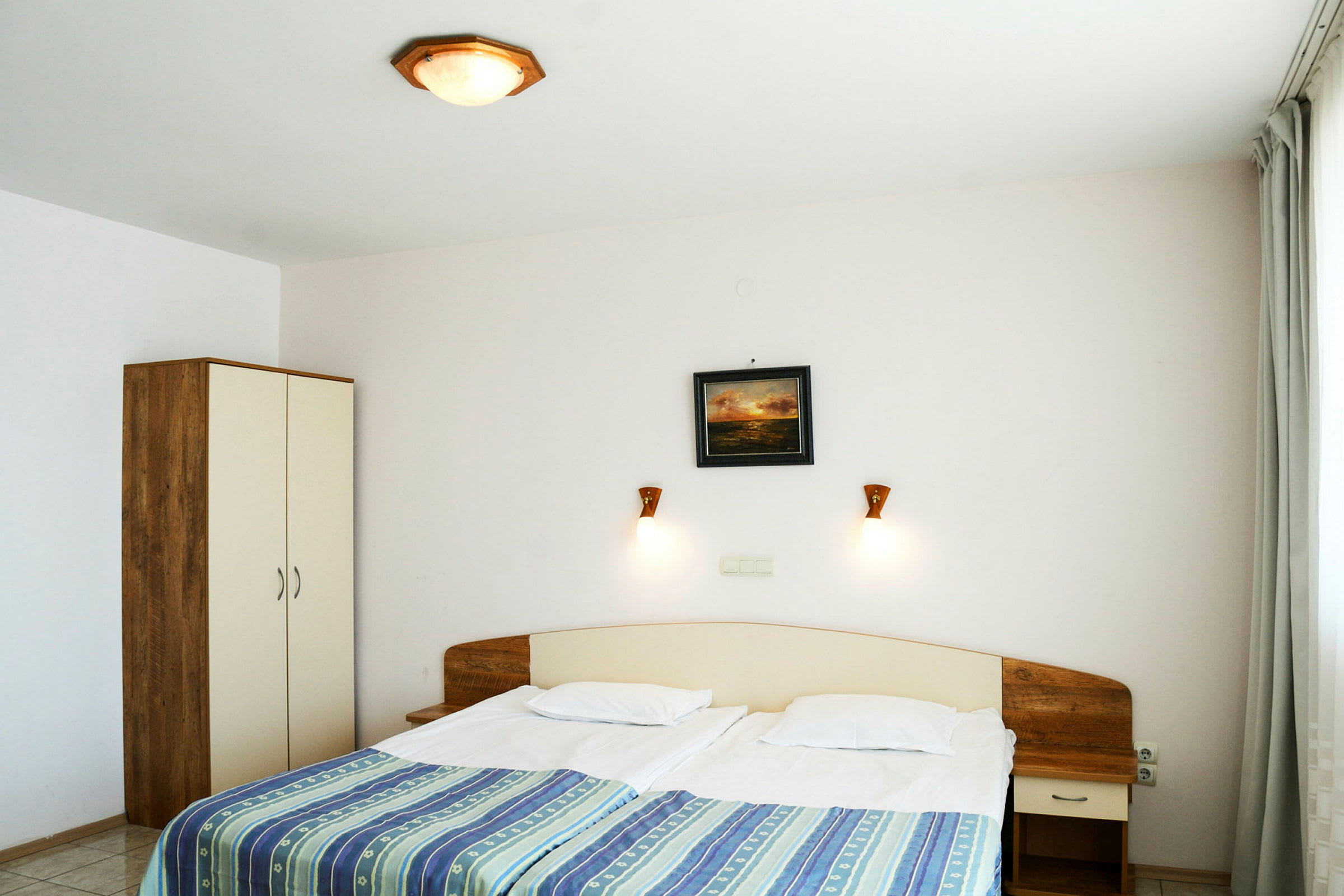 Et hotellrom med en dobbeltseng, nattbord og garderobe. (AI-generert tekst)