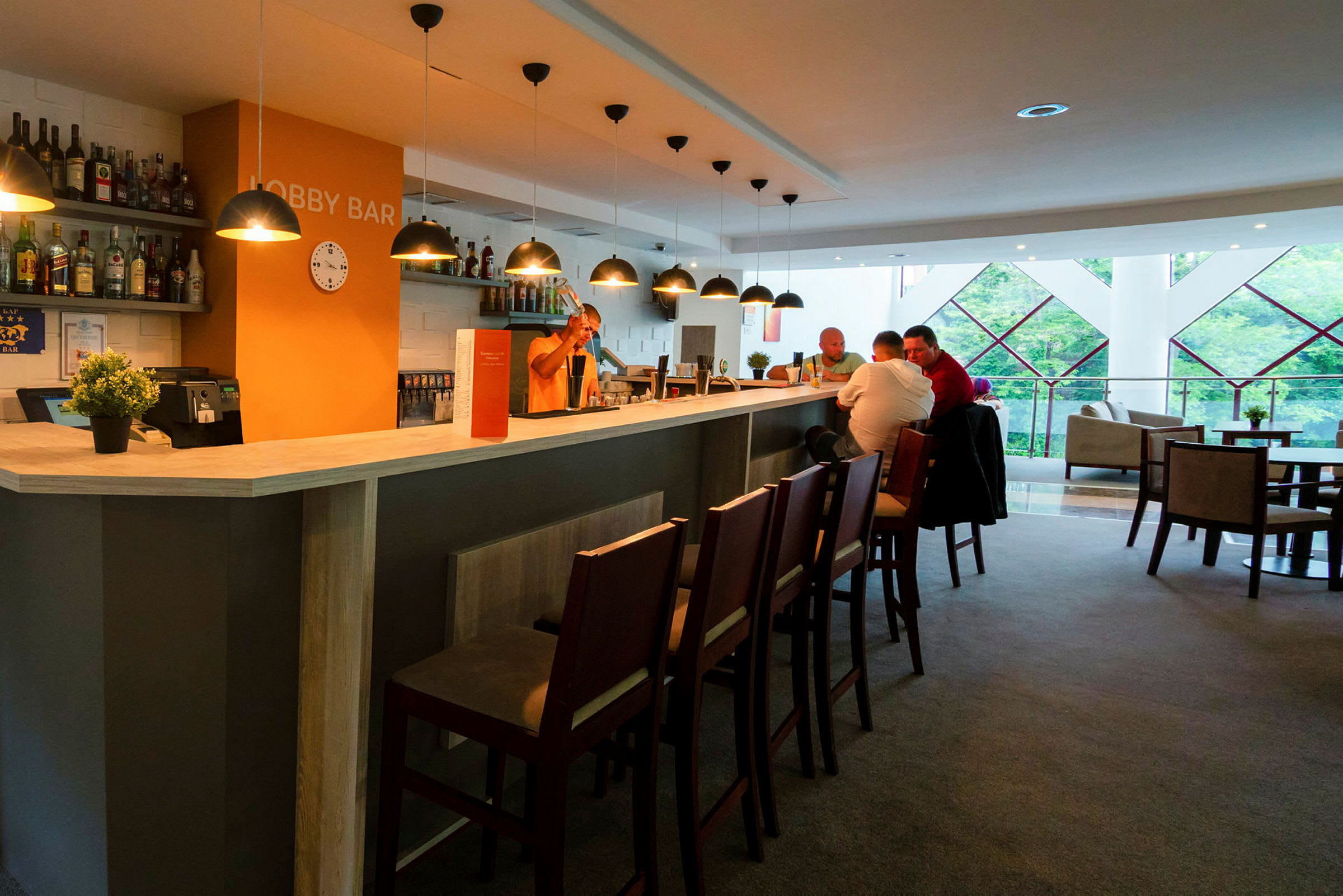 En lobbybar med belysning, stoler og mennesker som sitter ved disken. (AI-generert tekst)