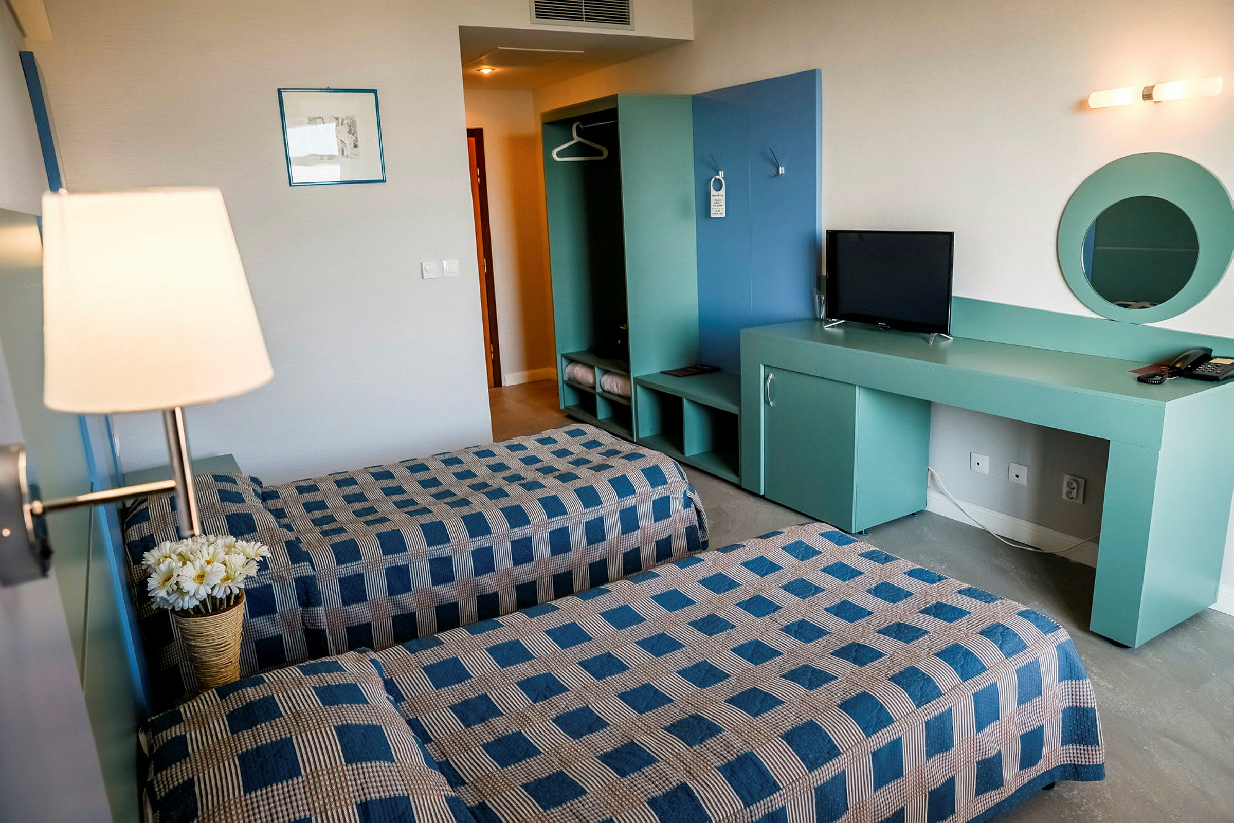 Et hotellrom med to enkeltsenger, TV og garderobe. (AI-generert tekst)