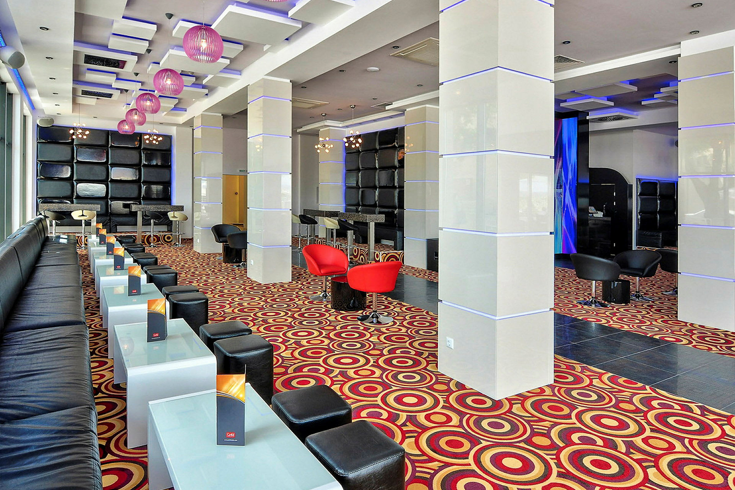 Moderne lounge med sitteplasser, glassbord og fargerikt gulvteppe. (AI-generert tekst)