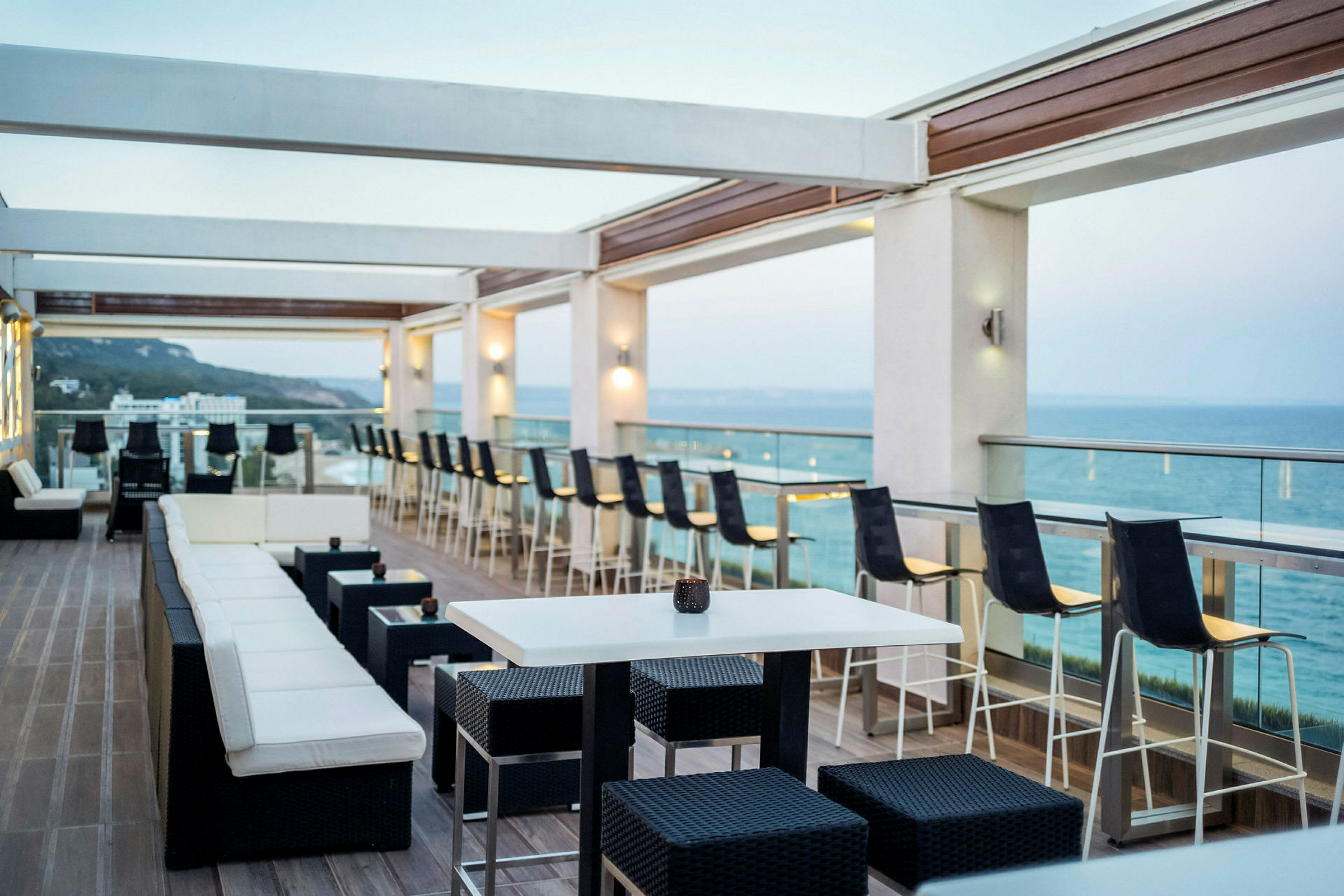 En åpen terrasse med sitteplasser og utsikt mot havet. (AI-generert tekst)