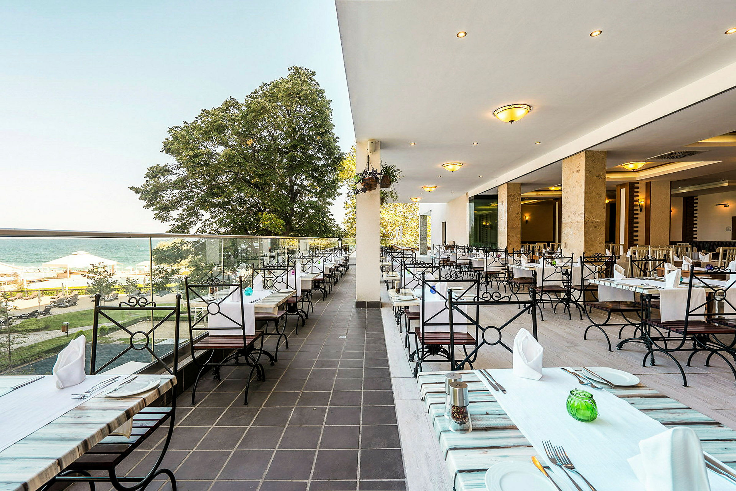 En åpen restaurantterrasse med havutsikt og sittegrupper. (AI-generert tekst)