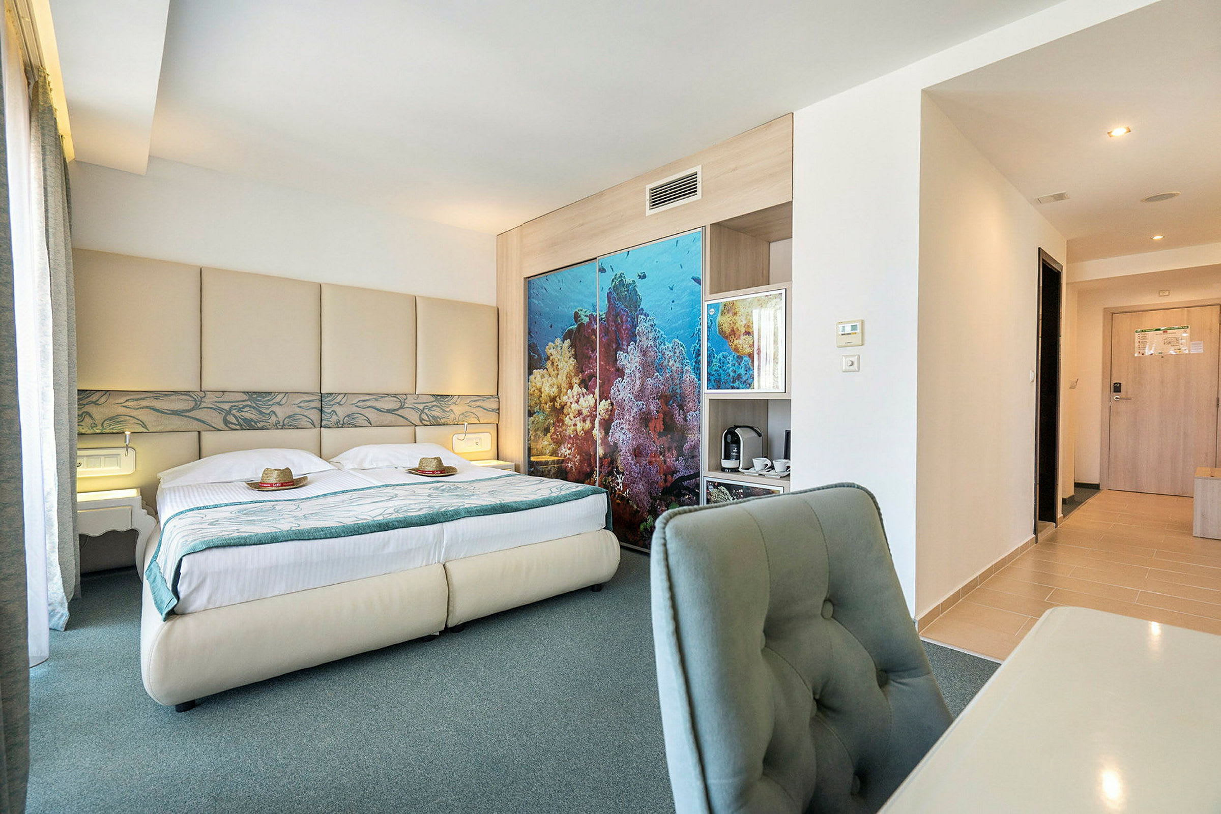 Bilde av et hotellrom med en dobbeltseng, havsinspirert dekor bak sengen og skrivebord med stol. (AI-generert tekst)