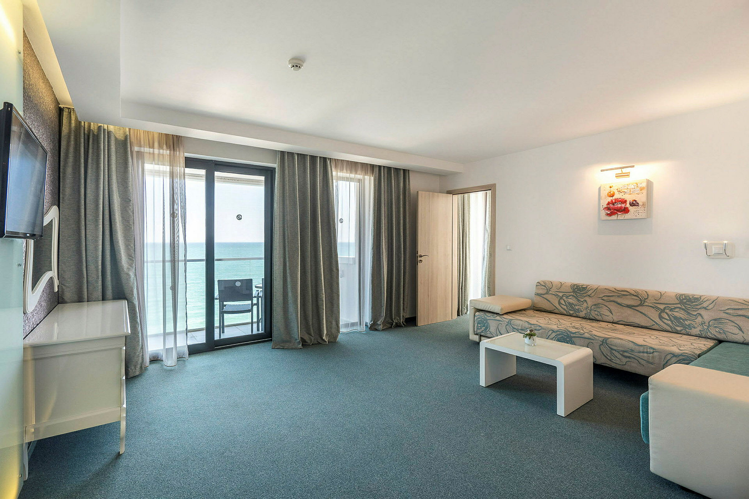 Et hotellrom med sittegruppe og balkongutsikt. (AI-generert tekst)