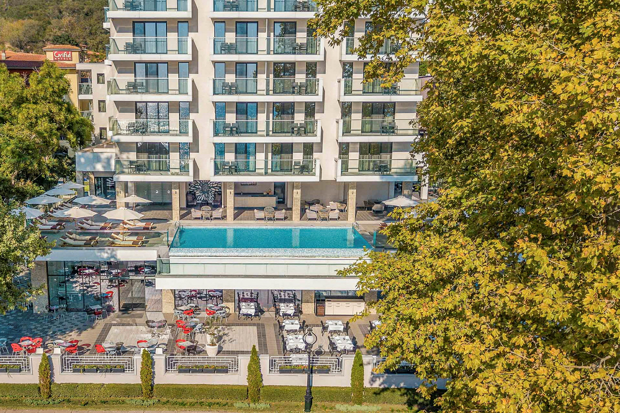 Flerebygningskompleks med utendørsbasseng og terrasse. (AI-generert tekst)