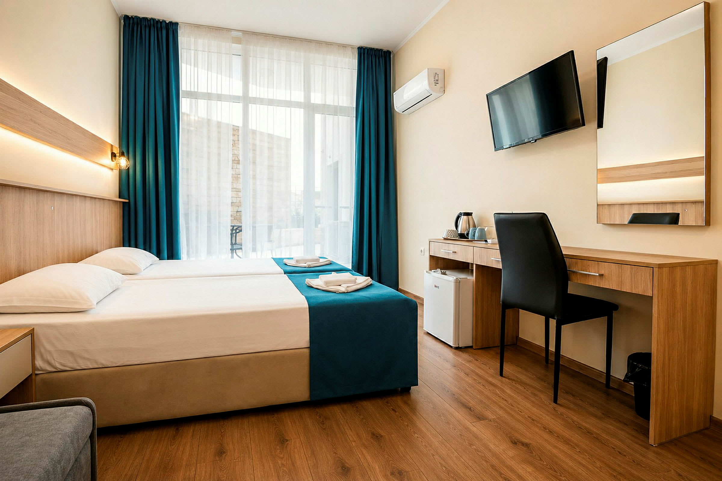 Et hotellrom med en dobbeltseng, skrivebord, stol, veggmontert TV og store vinduer med mørkeblå gardiner. (AI-generert tekst)