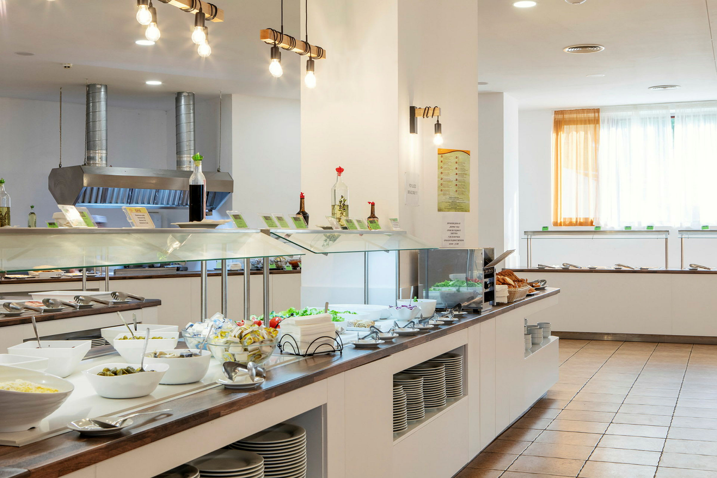 Bilde av en buffet med salater, tilbehør og skåler i en lys spisesal. (AI-generert tekst)
