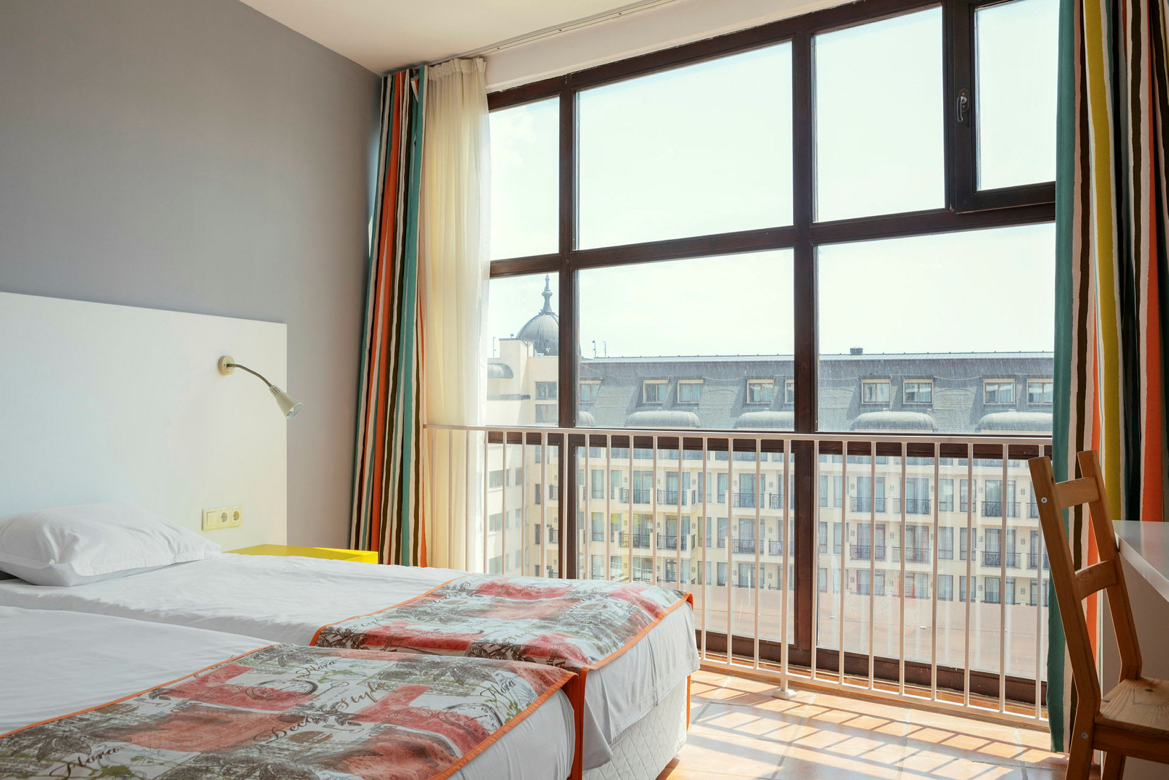 Hotellrom med to enkeltsenger og stort vindu mot byutsikt. (AI-generert tekst)