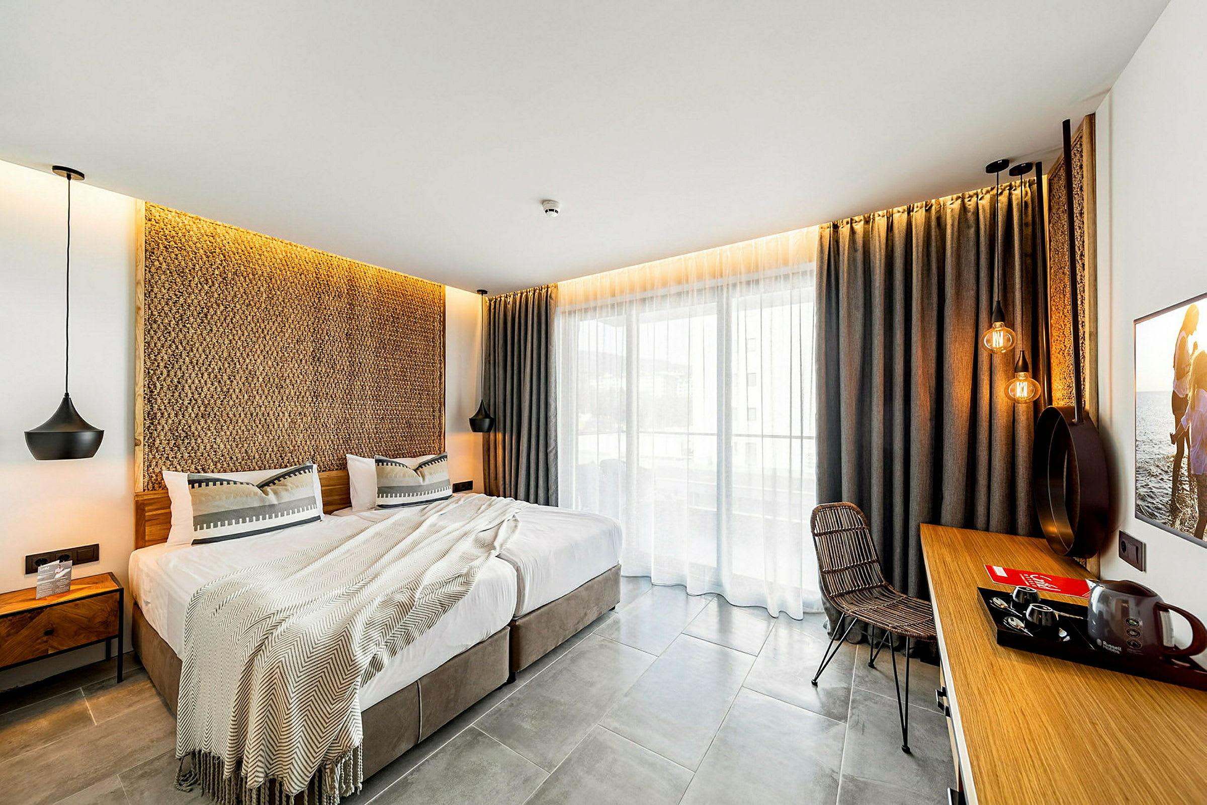 Moderne innredet hotellrom med dobbeltseng, sittegruppe og balkong. (AI-generert tekst)
