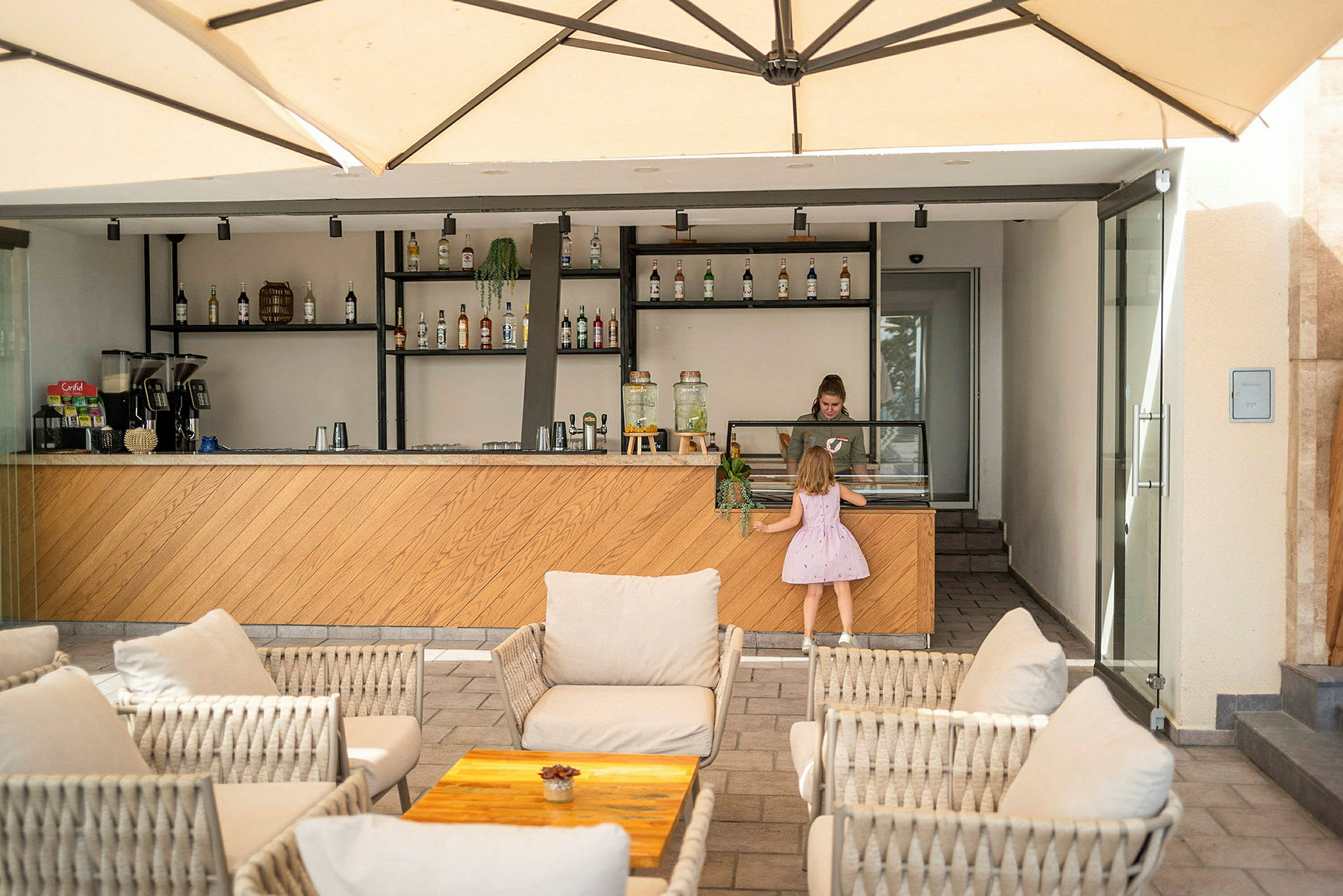Loungeområde med sitteplasser og en bar med diverse flasker på hyller. (AI-generert tekst)