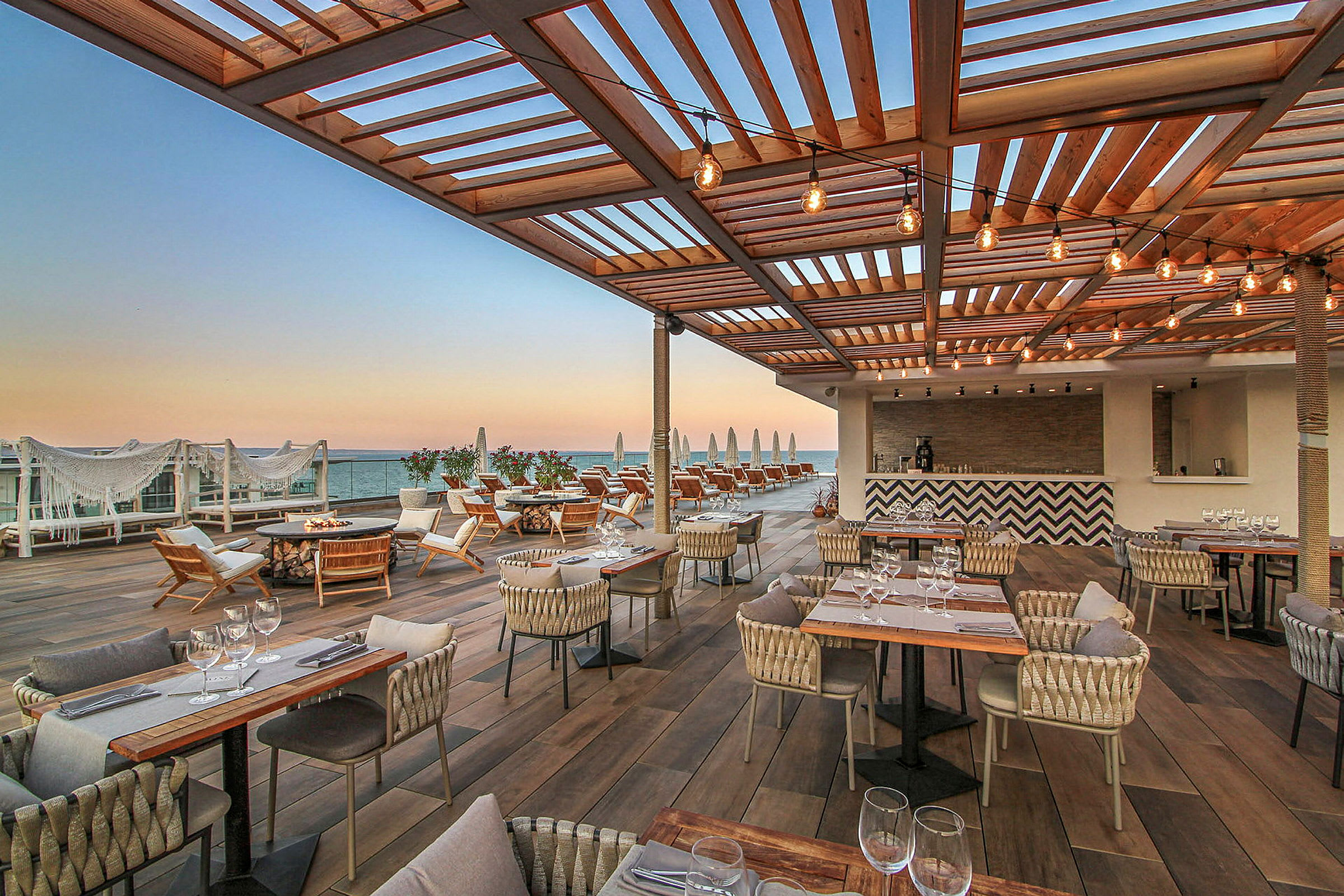 Restaurant med terrasse og havutsikt under trepergola. (AI-generert tekst)