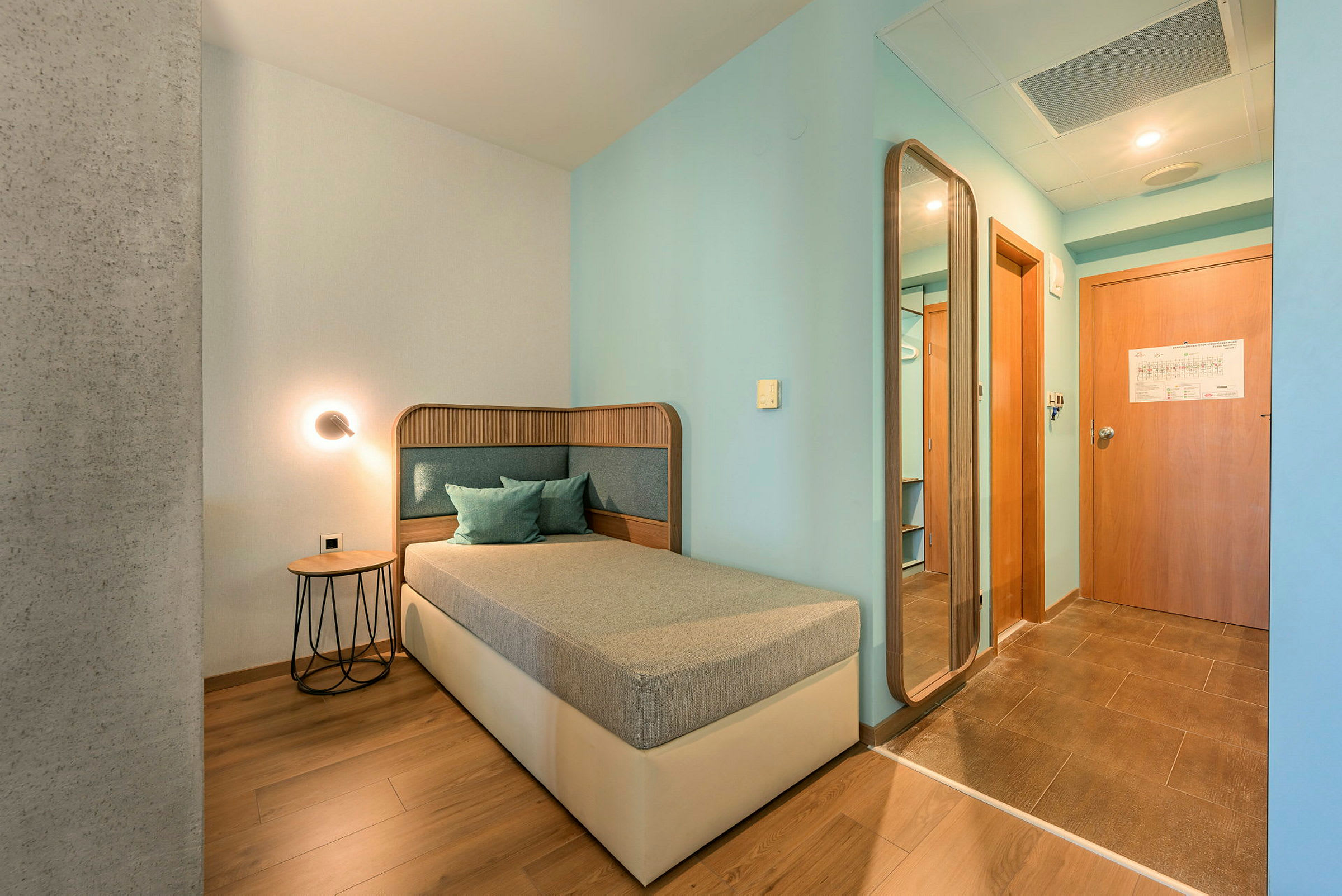 Hotellrom med enkeltseng, bord og speil. (AI-generert tekst)