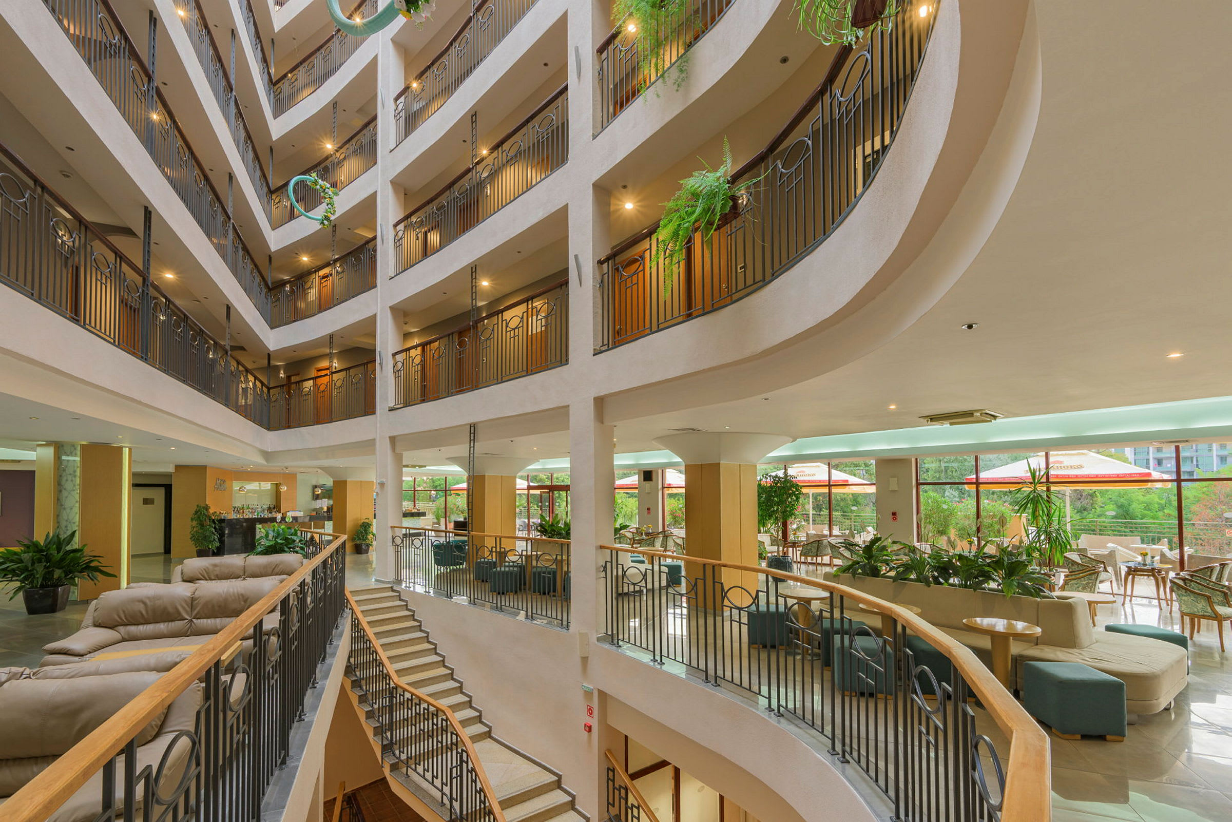 Interiør av et hotell med fleretasjes atrium, sittegrupper og planter. (AI-generert tekst)