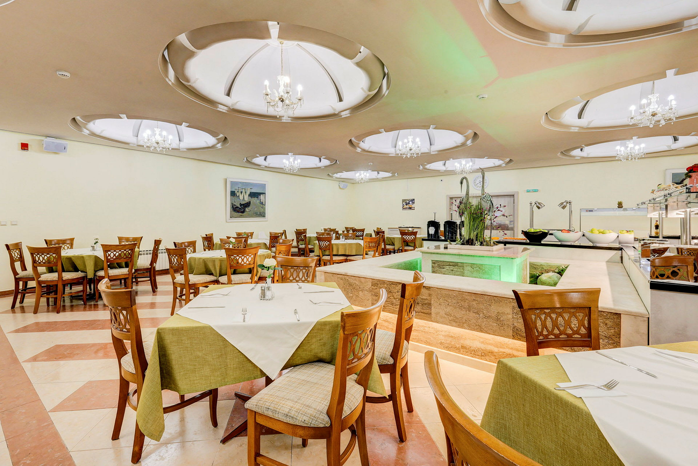 Bilde av en restaurant med trestoler og bord dekket med grønne duker. I bakgrunnen vises dekorasjoner og en buffé. (AI-generert tekst)