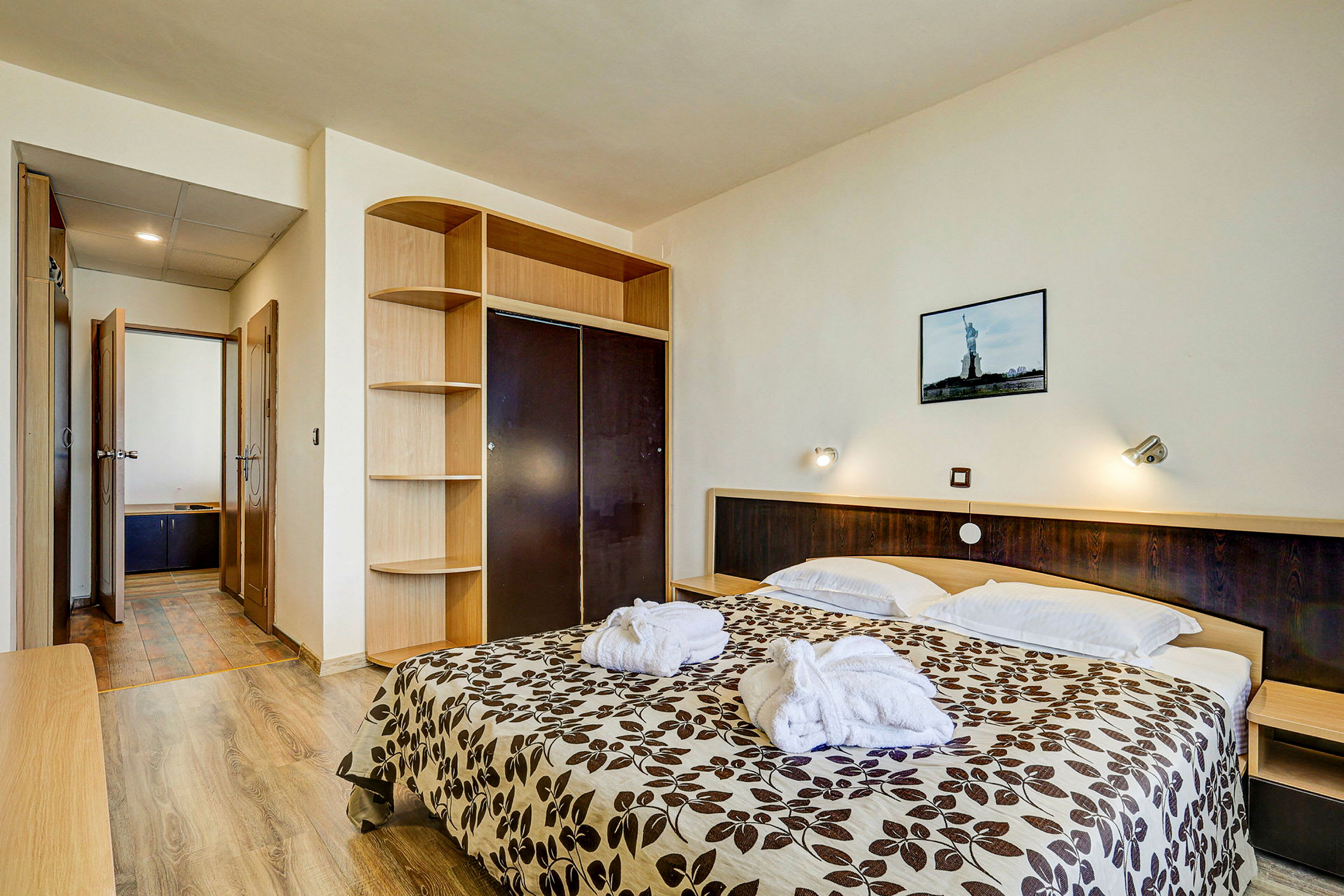Et hotellrom med en dobbeltseng, et nattbord, en garderobe og et bad i bakgrunnen. (AI-generert tekst)