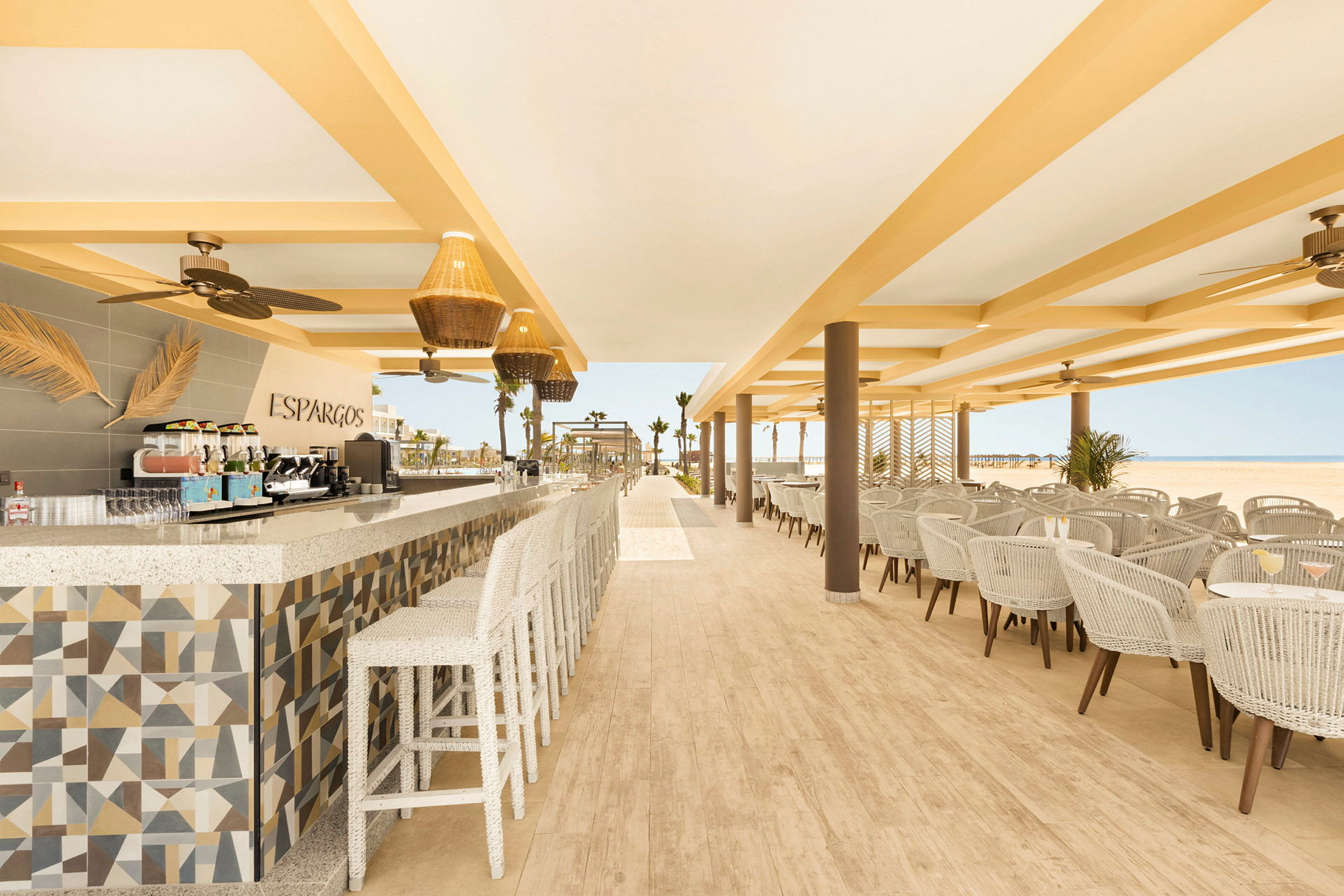En åpen og lys restaurant med sitteplasser, tak, vifter og et velorganisert matlagingsområde. (AI-generert tekst)