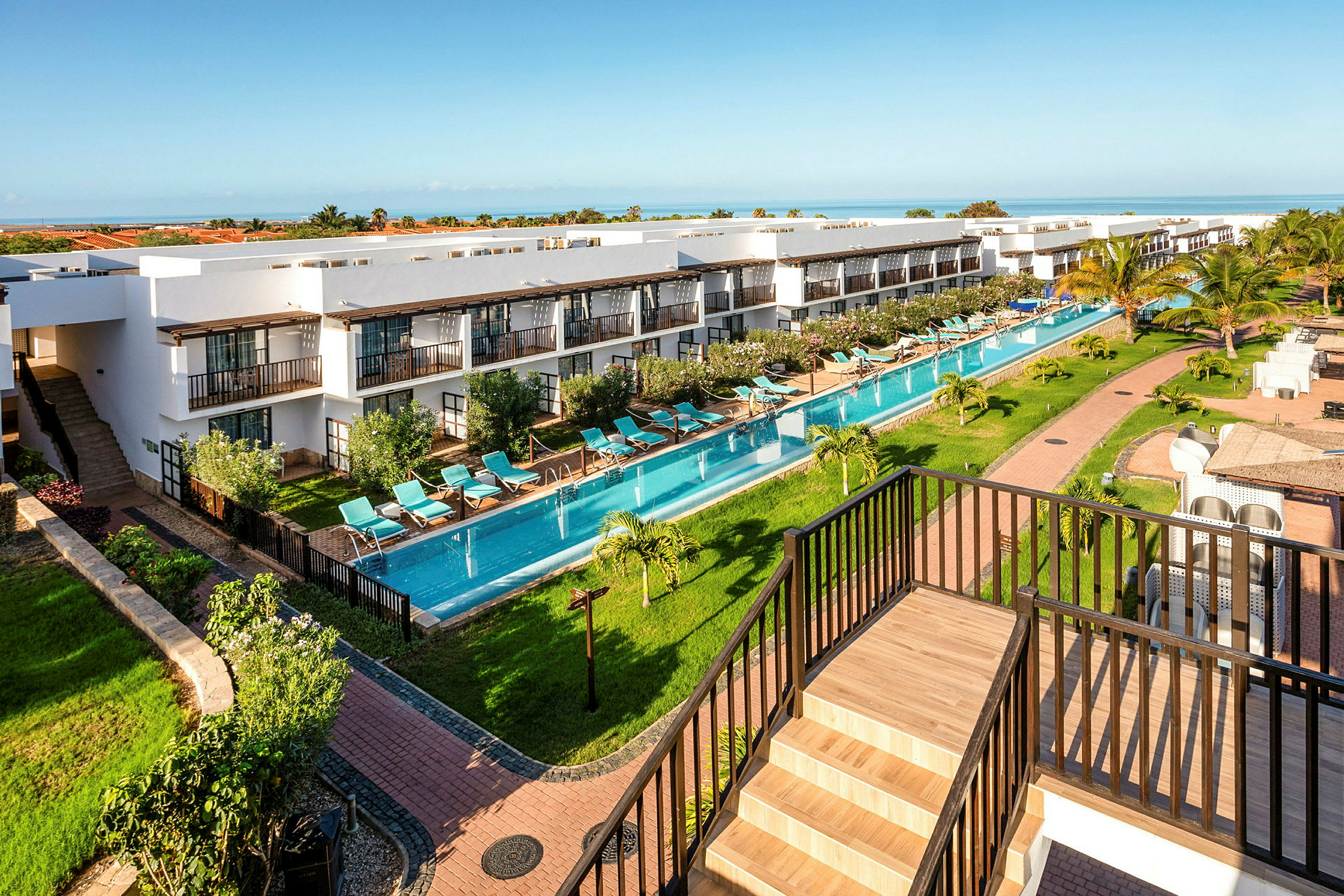 En oversikt over en resort med bygninger, et langt basseng og frodige omgivelser. (AI-generert tekst)