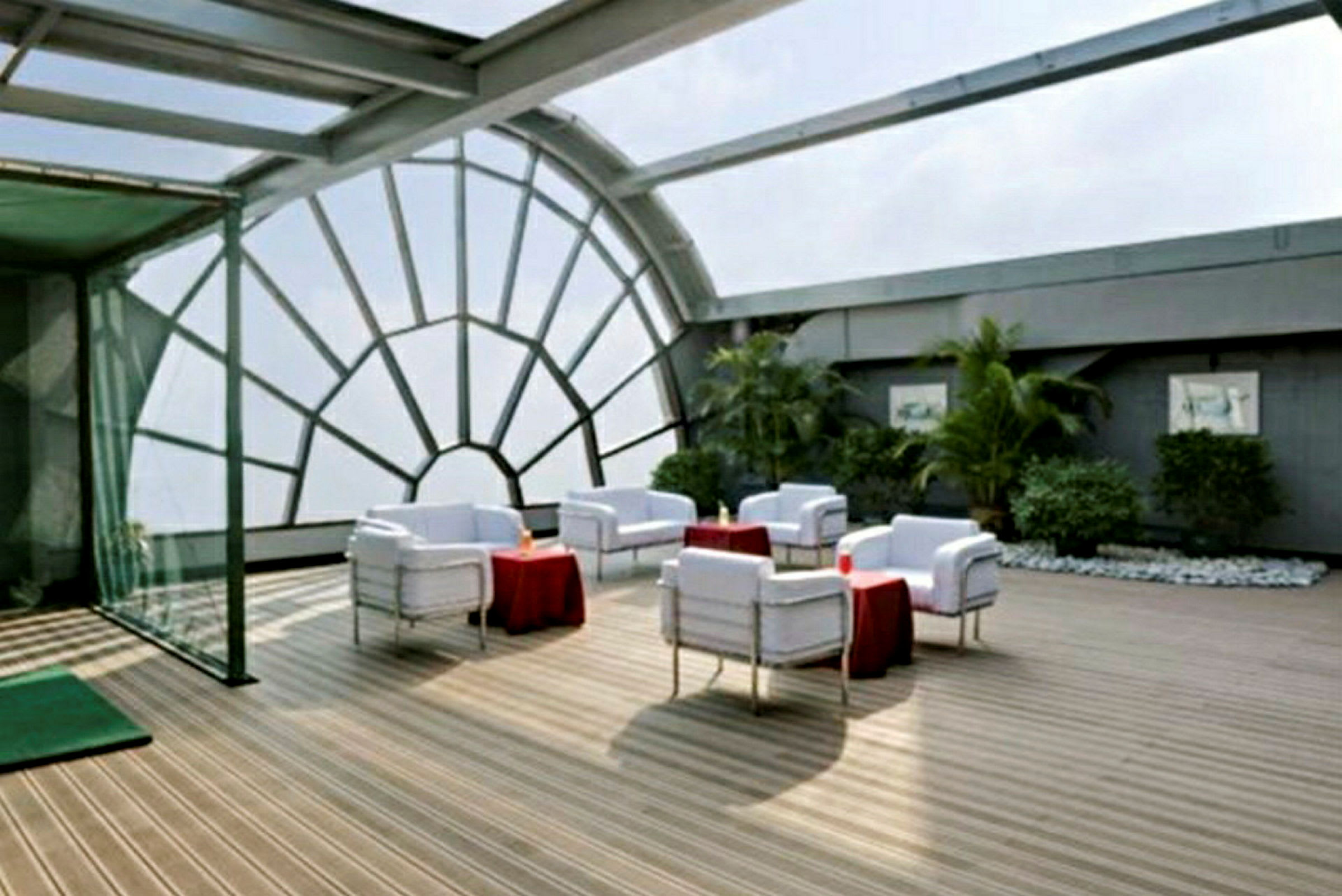 En moderne takterrasse med sittegrupper og en glassvegg med buet mønster. (AI-generert tekst)