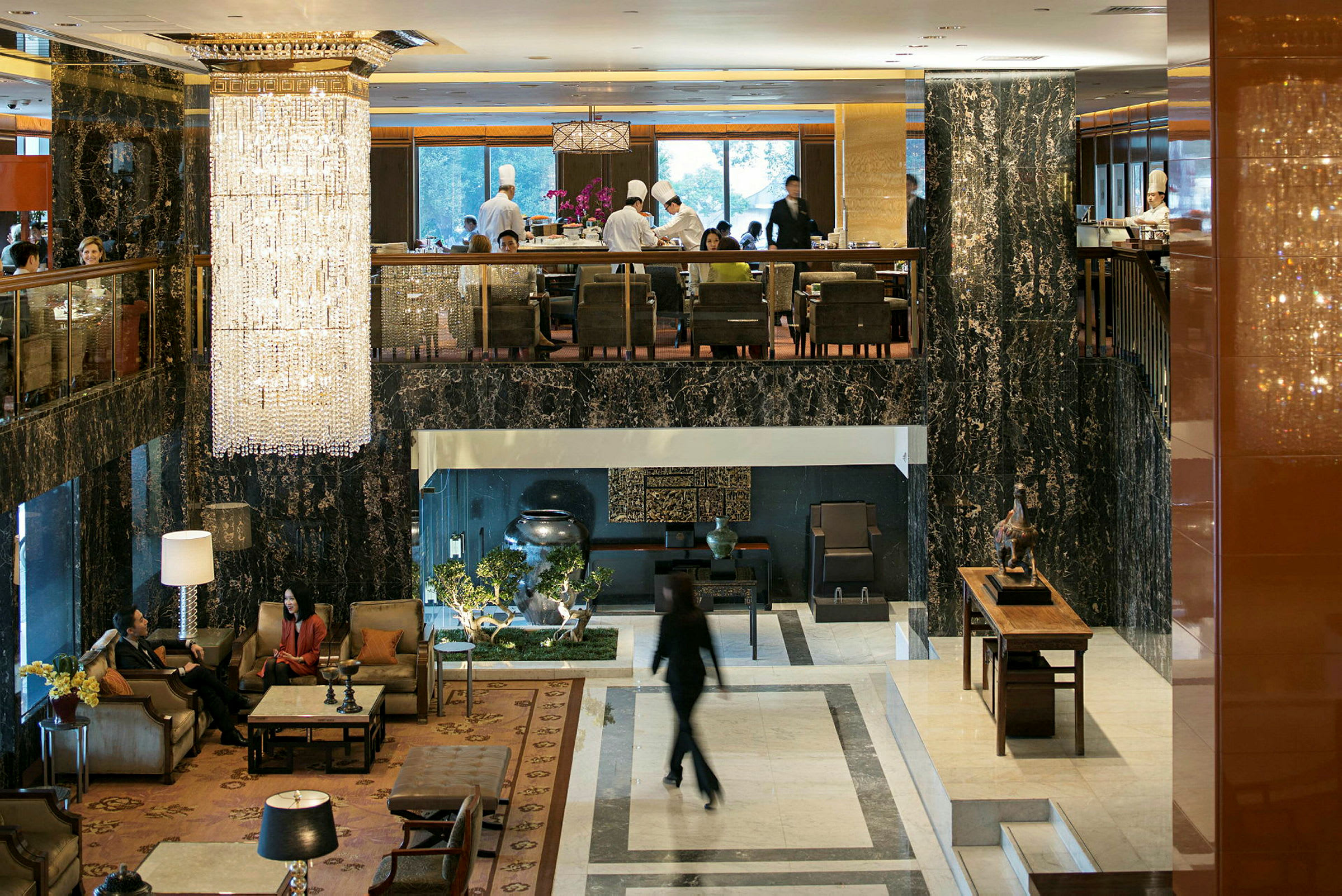 Hotellobby med elegante møbler, store vinduer og en stor krystallkrone som henger fra taket. (AI-generert tekst)