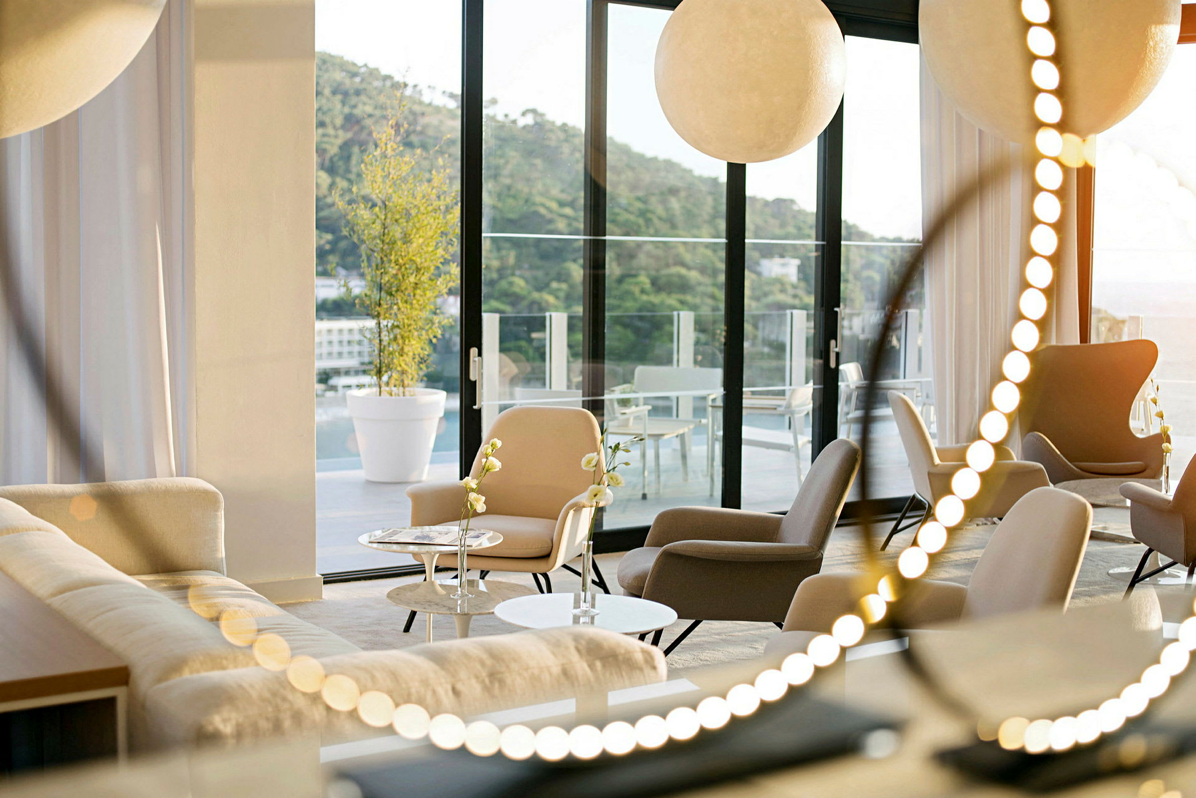 Et moderne rom med sitteplasser og sofaer, store vinduer som vender mot en terrasse. (AI-generert tekst)