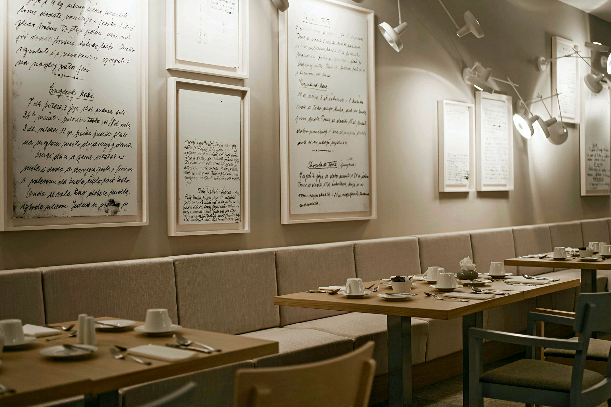 En elegant restaurant med bord dekket til middag og dekorert med minimalistiske bilder på veggen. (AI-generert tekst)